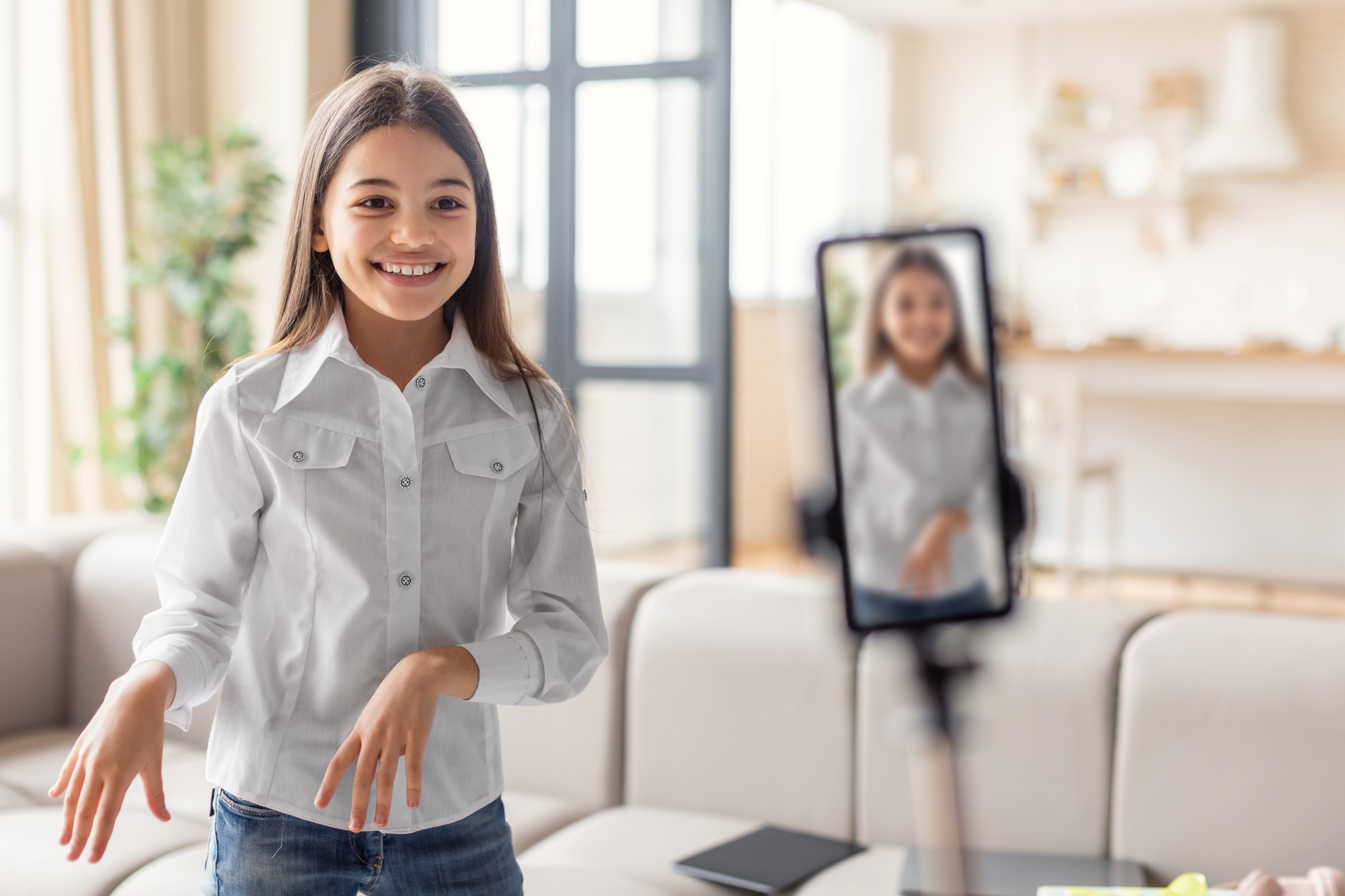 Cheerful Preteen Blogger Girl Dancing At Phone Making Video Indoors