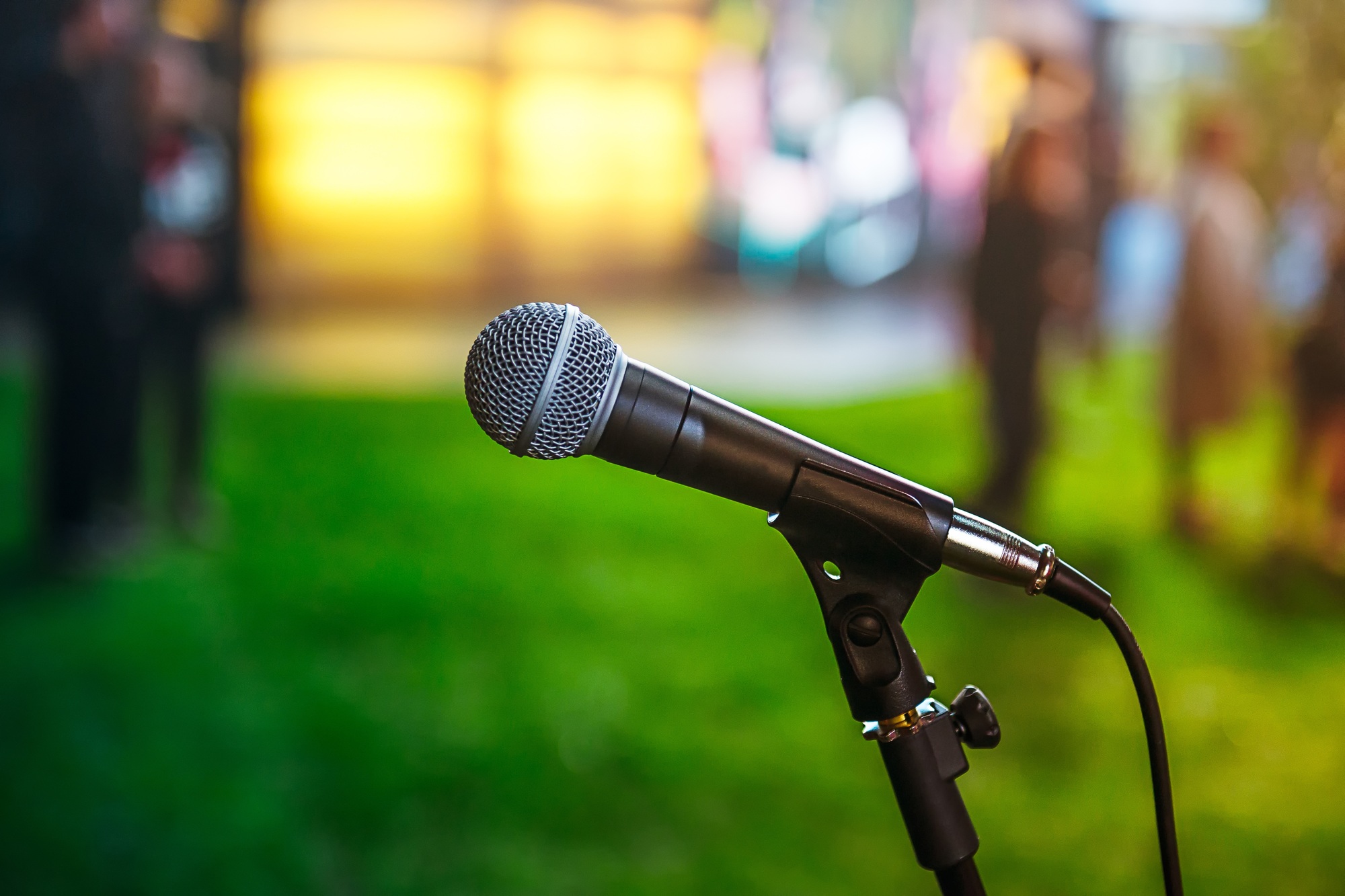 classic microphone on Abstract blurred bright green background of conference hall or event. Public s