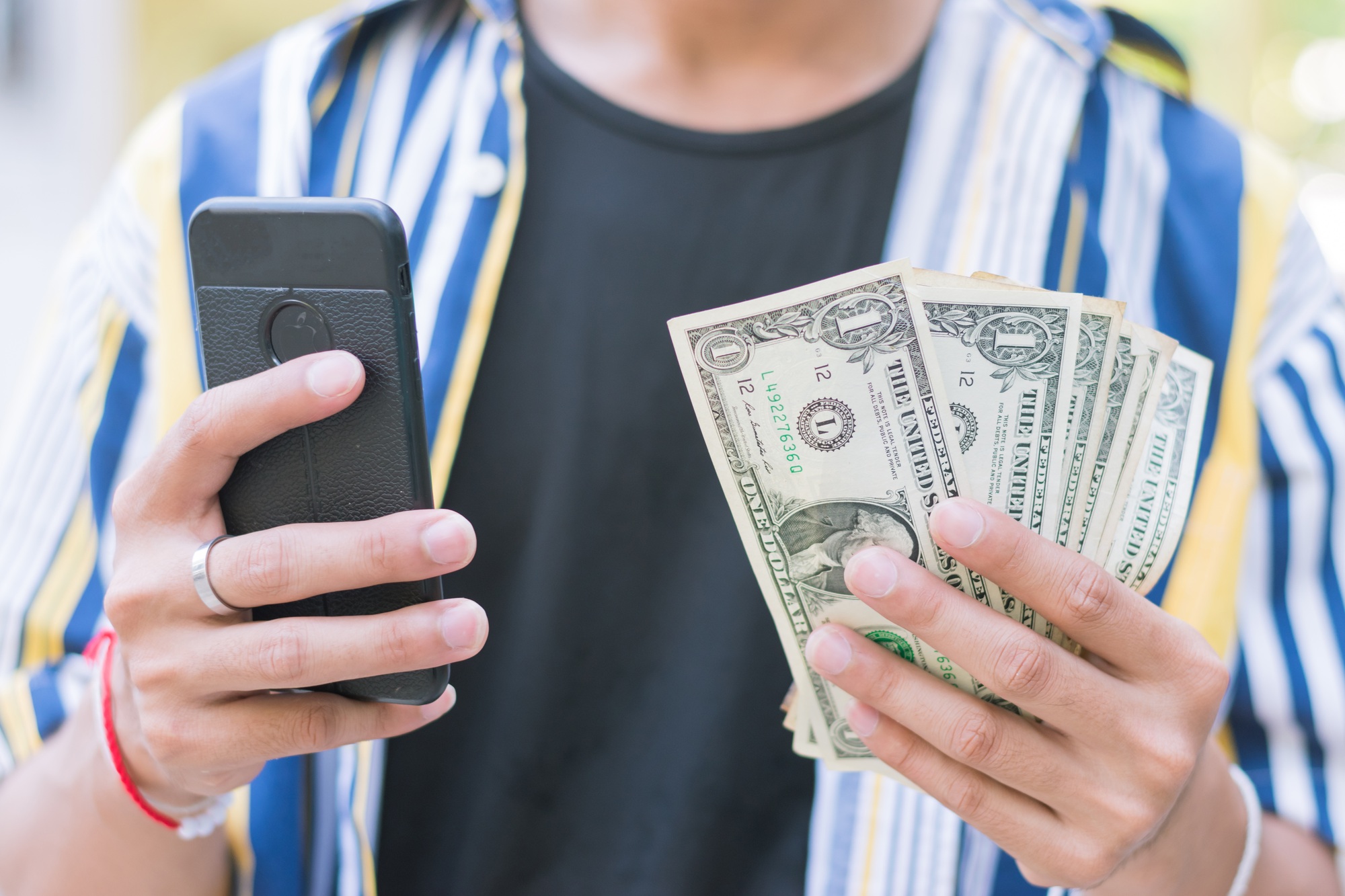 close up adult Asian guy man wearing colorful t-shirt holding US dollars money cash