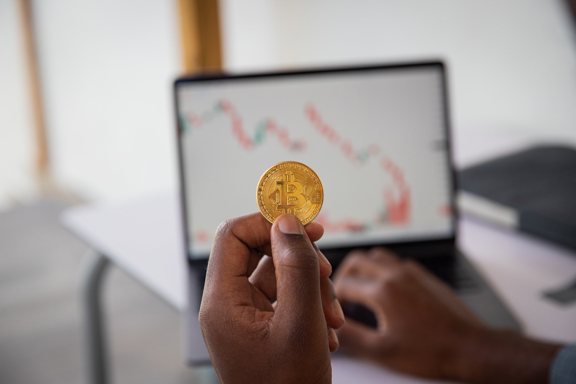 Close-up of a bitcoin coin held in hand by an investor who checks the value of the cryptocurrency