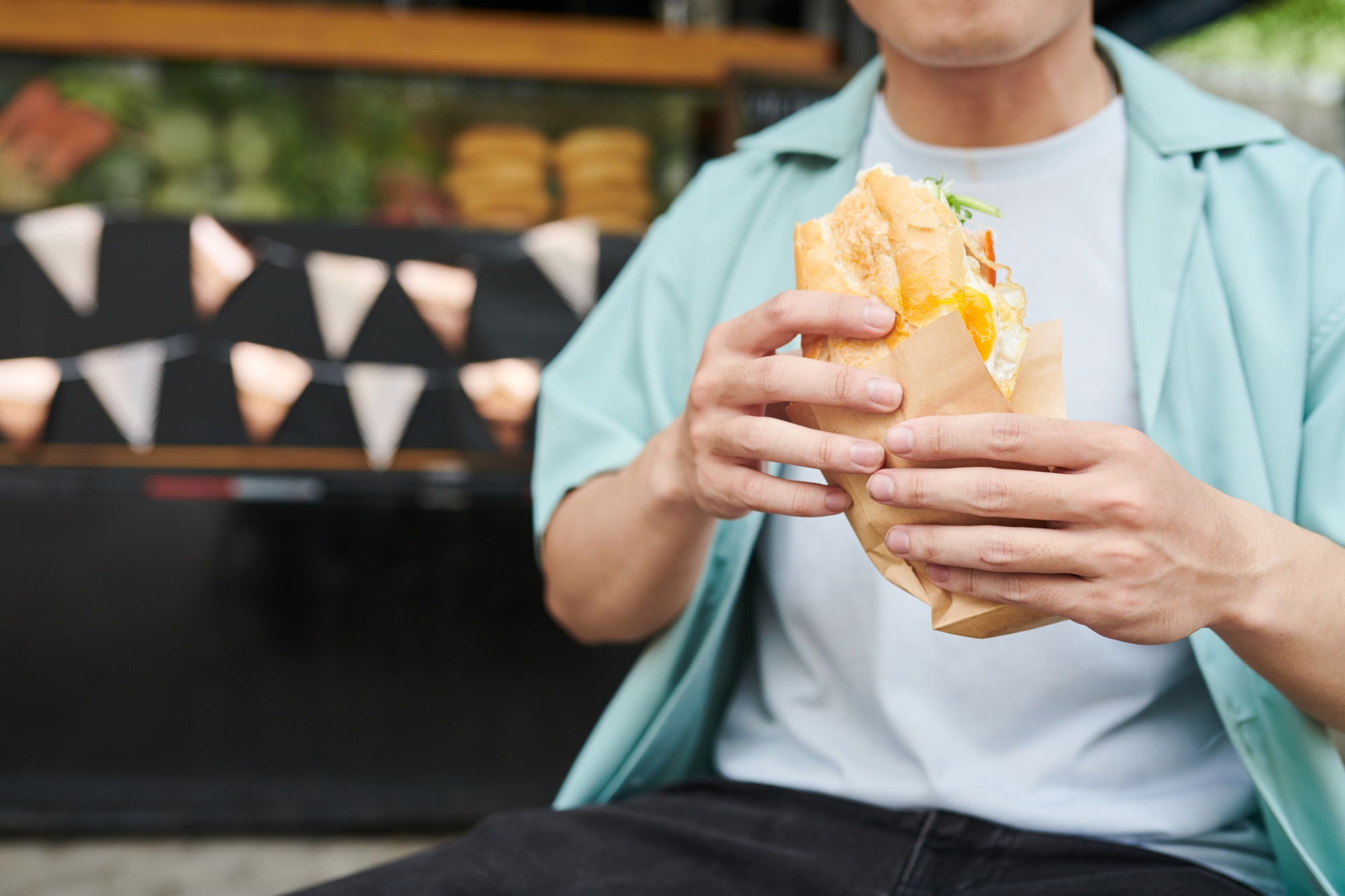 Close-up of young hungry man in casualwear holding appetizing hotdog