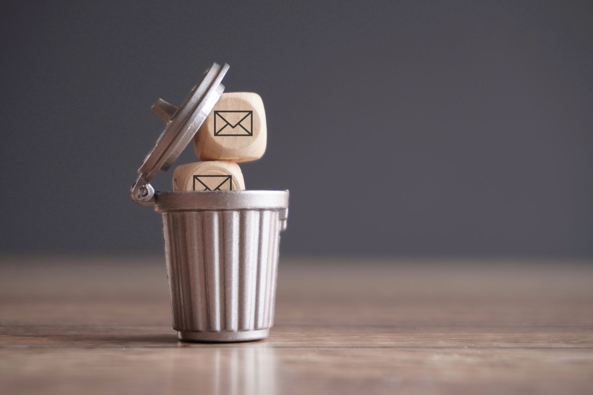 Closeup image of wooden cube with mail icon inside trash can.