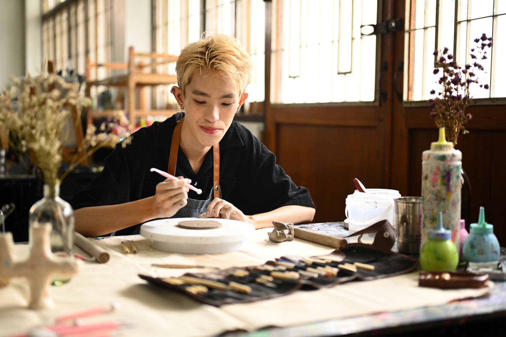 Concentrated young man shaping and decorating pottery in workshop.