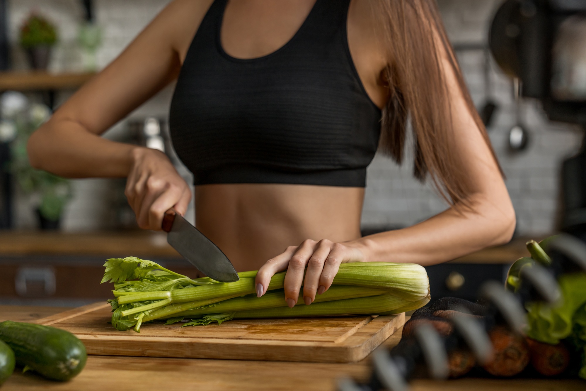 Cropped image of woman cutting celery in kitchen and recording it on video for blog