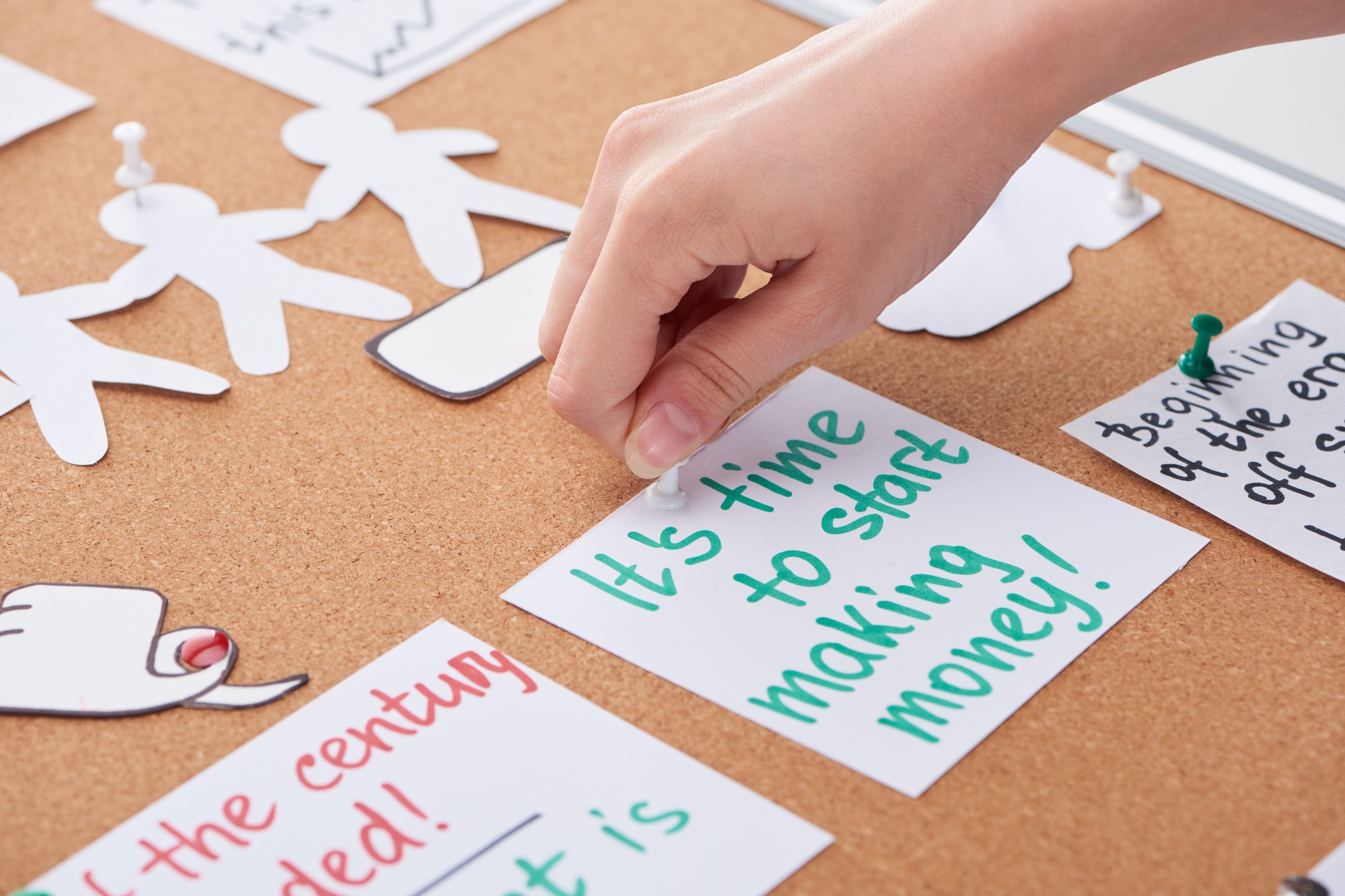cropped view of woman pinning card with work notes on cork board