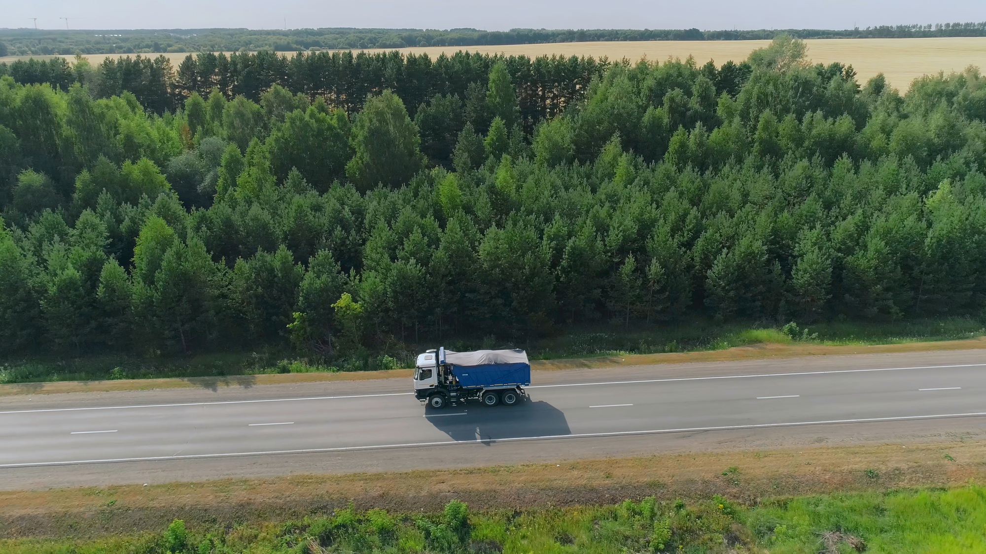 Dump truck driving on highway. Scene. Top view of dump truck on highway in summer. Truckers and dump