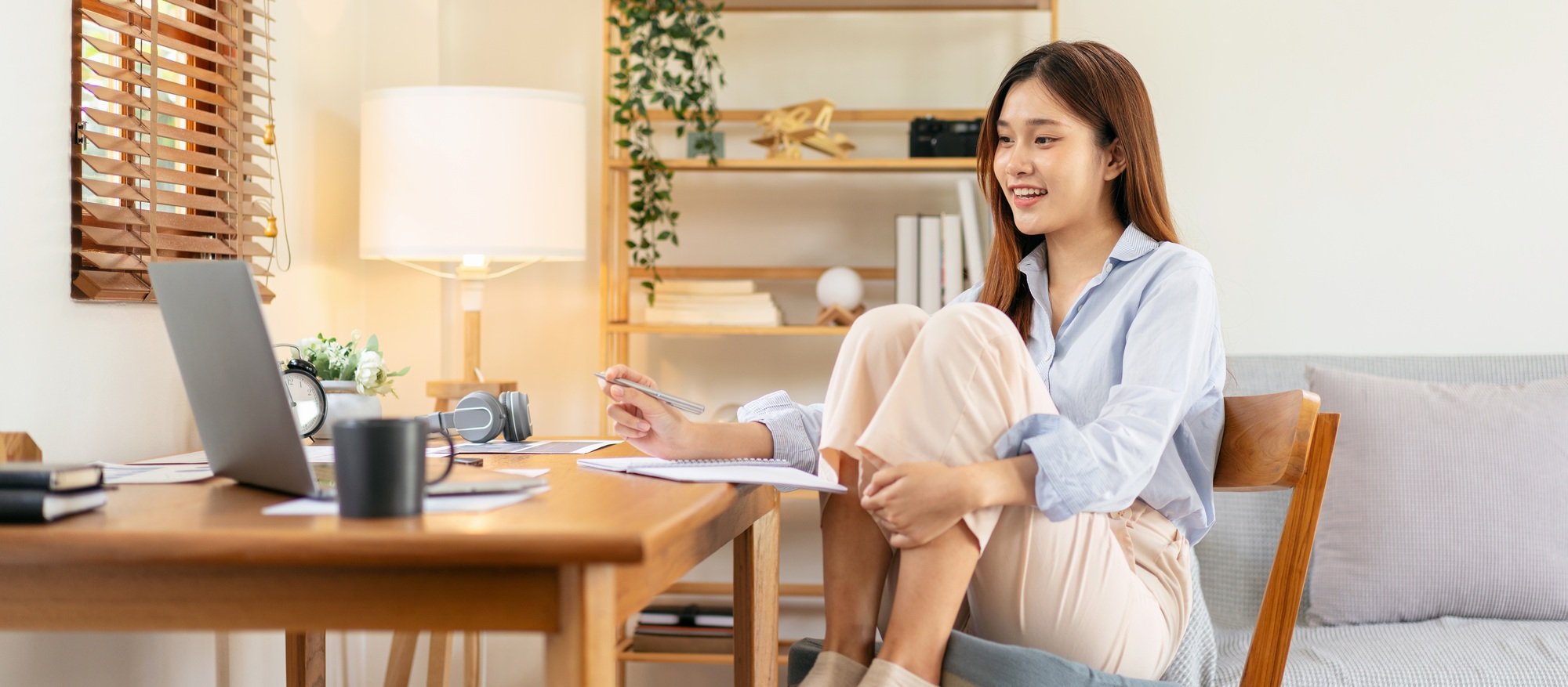 Female freelance is reading business data on laptop and writing