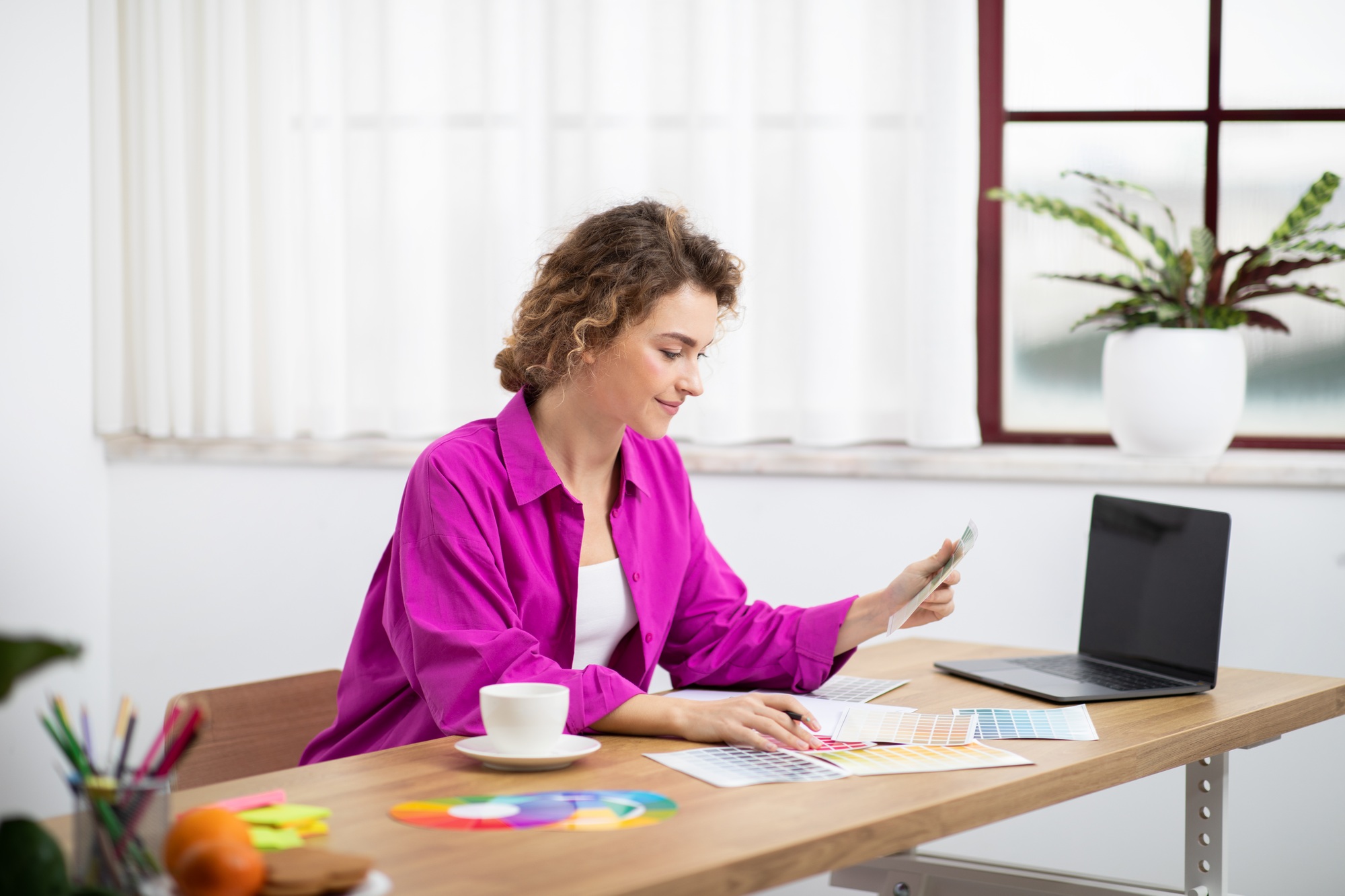 Female Graphic Designer Working With Laptop And Color Swatches In Home Office