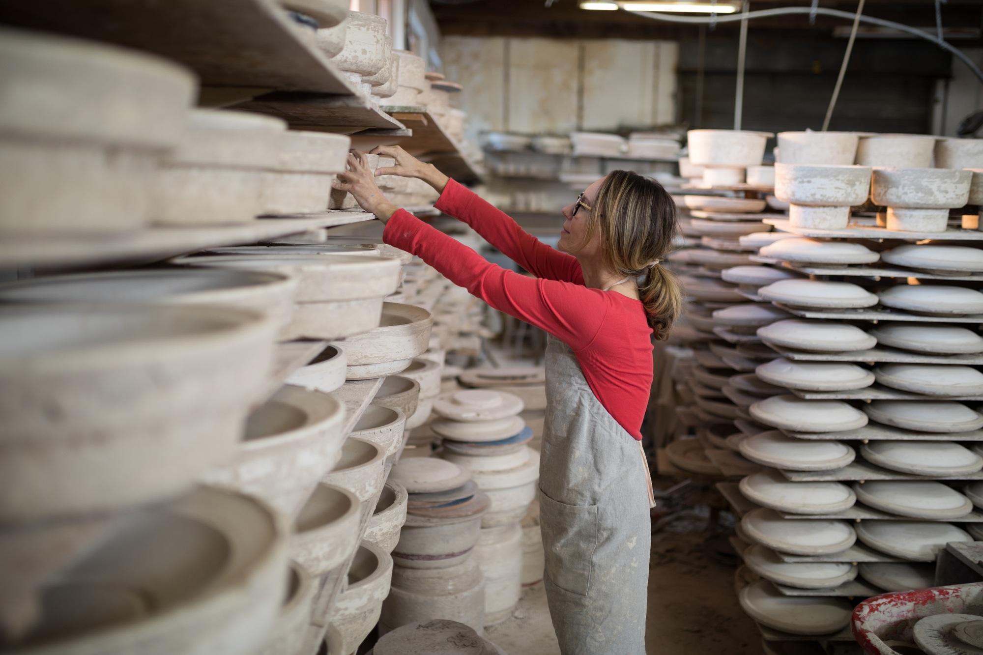 Female potter placing craft product in shelf
