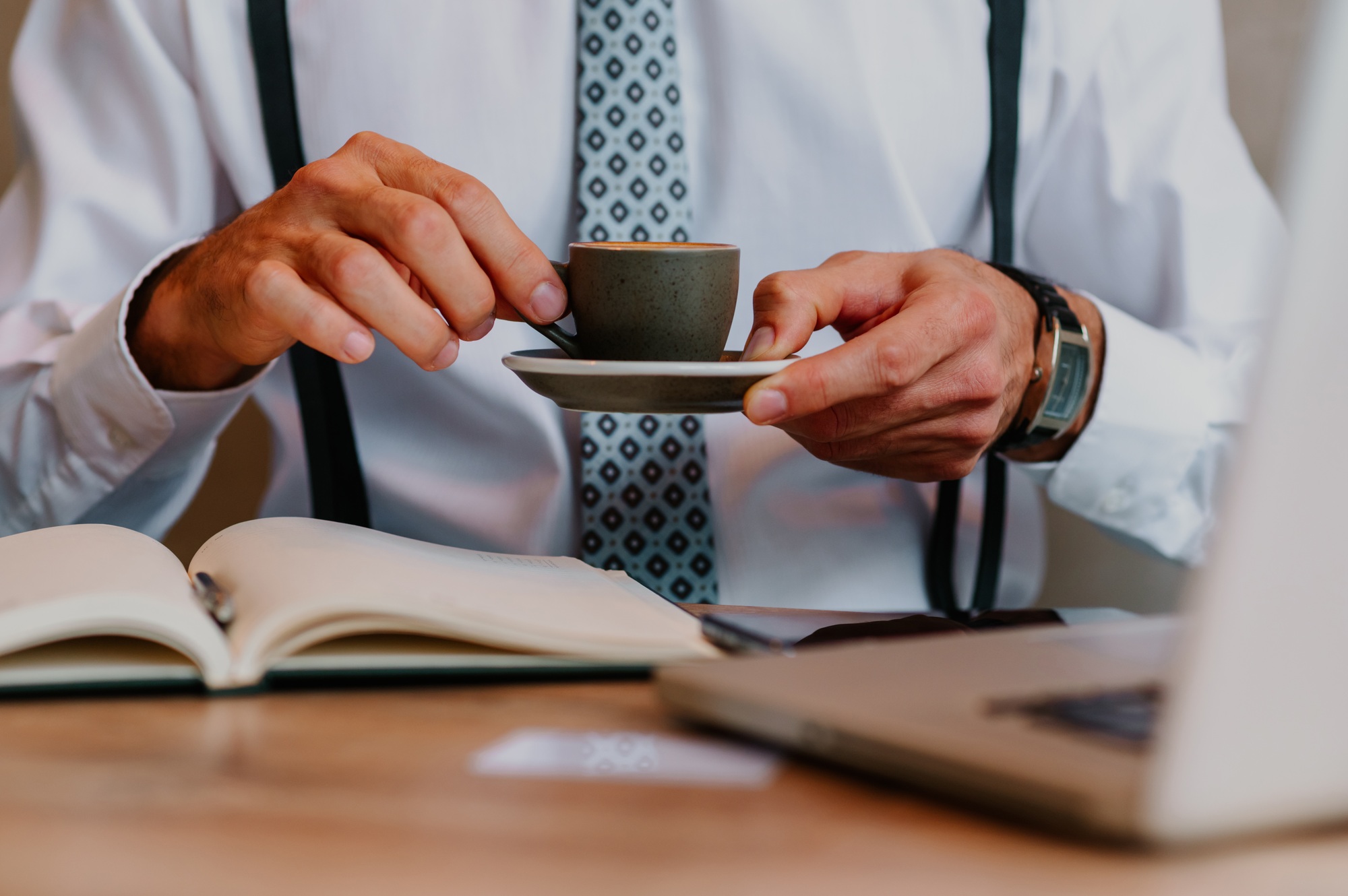 Focus on man's hands holding a small cup of espresso coffee in his hands.