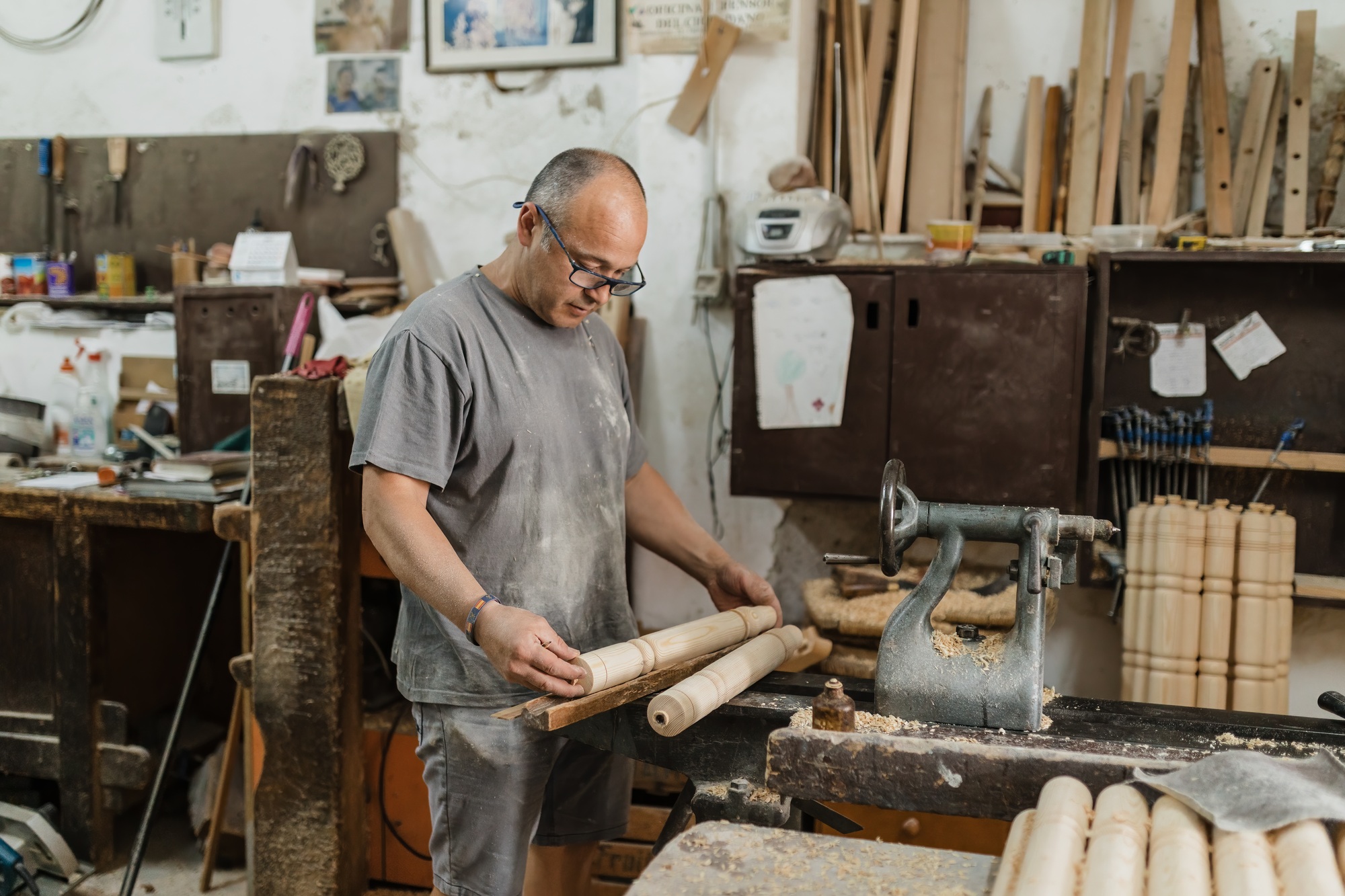 Focused adult ethnic carpenter standing and examining crafted wood work in daylight
