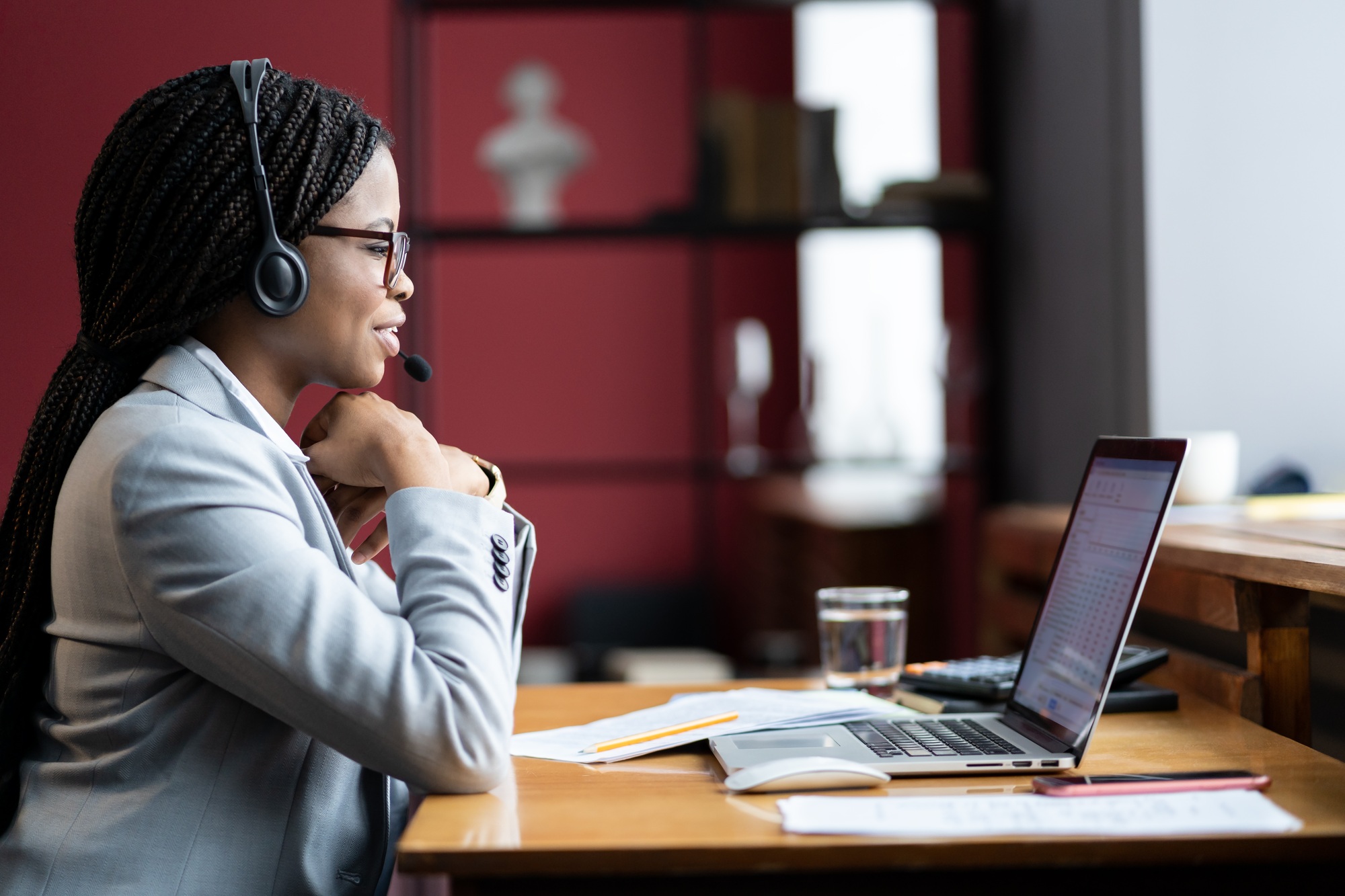 Focused businesswoman in headset listen to video conference call with client online sharing screen