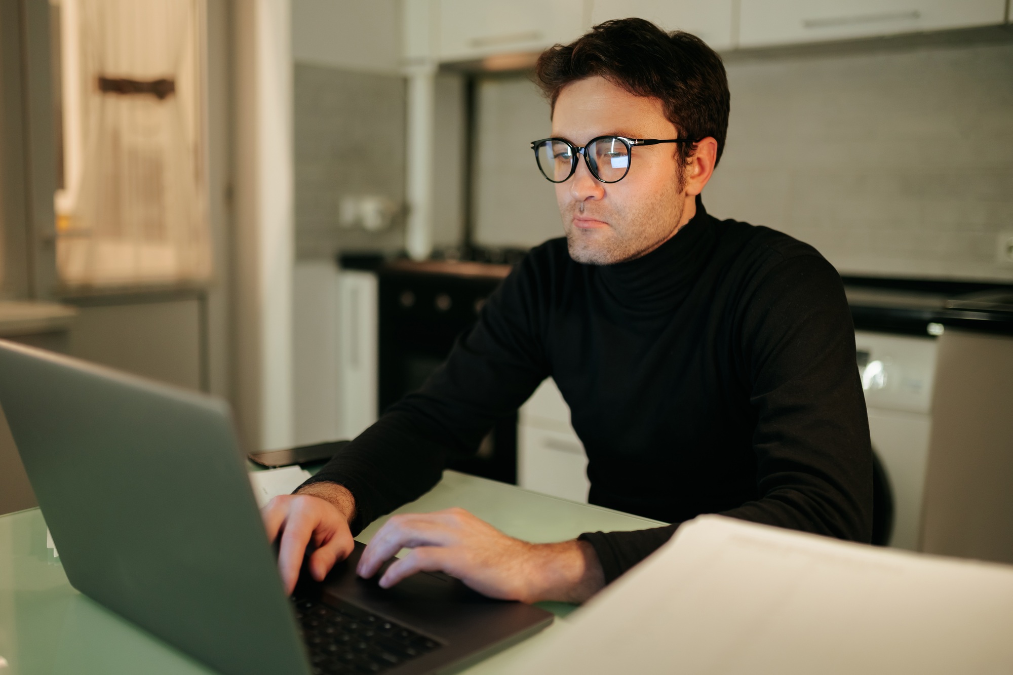 Focused young man working on laptop during evening hours at home
