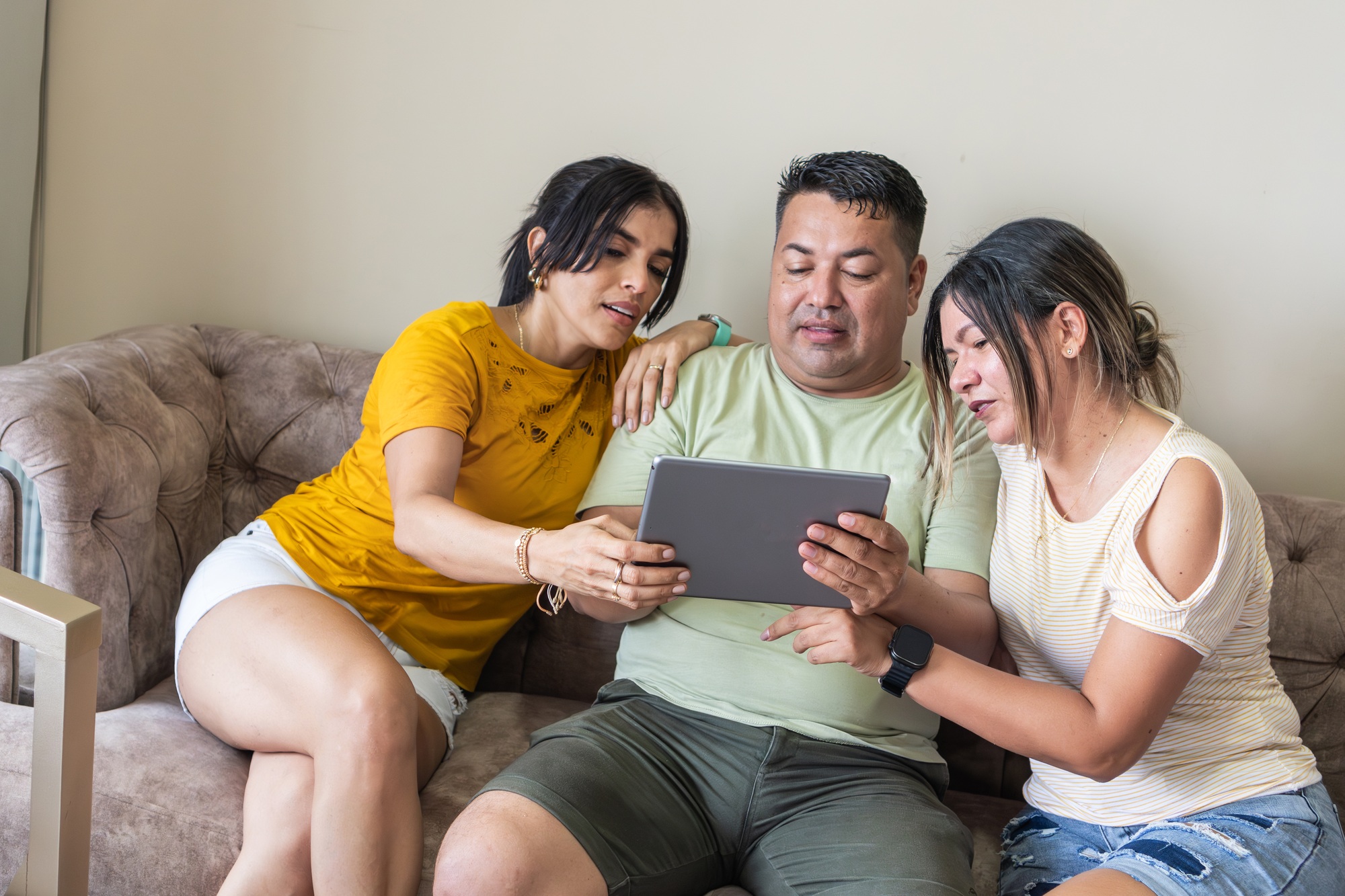 Friends Sharing a Tablet on a Sofa