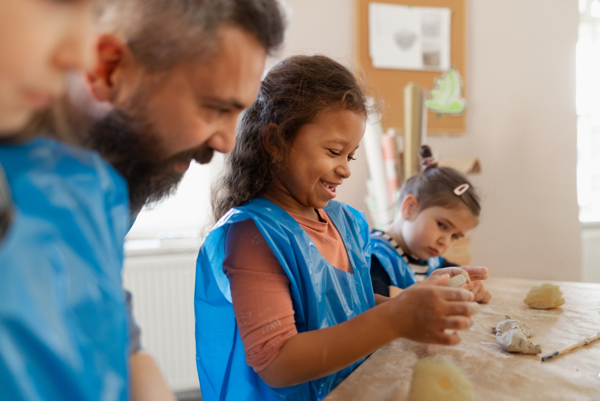 Group of little kids with teacher working with pottery clay during creative art and craft class at