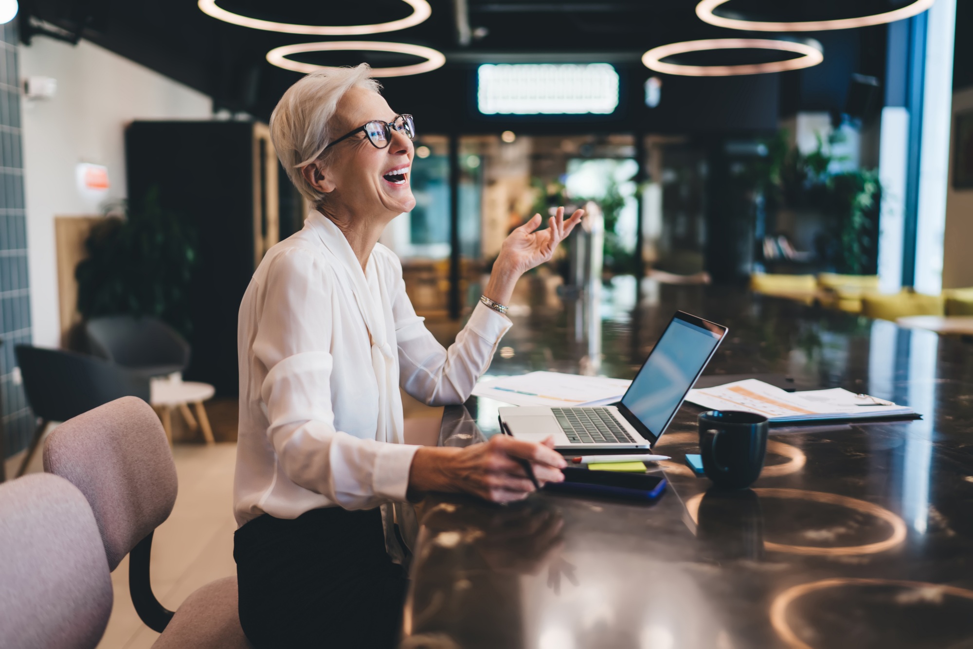 Happy businesswoman laughing while working on laptop at workplace