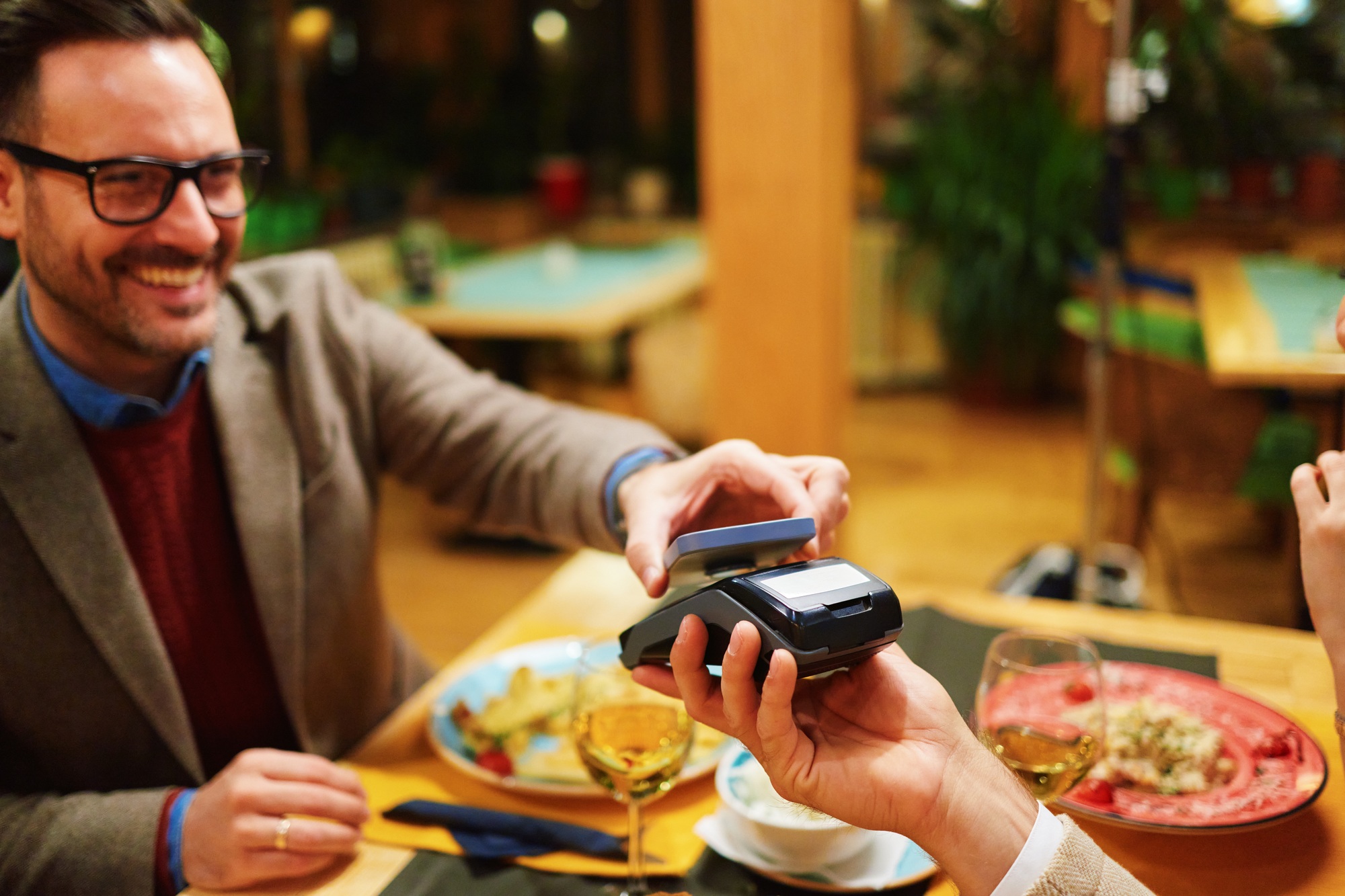 Happy customer paying restaurant bill with contactless mobile payment technology