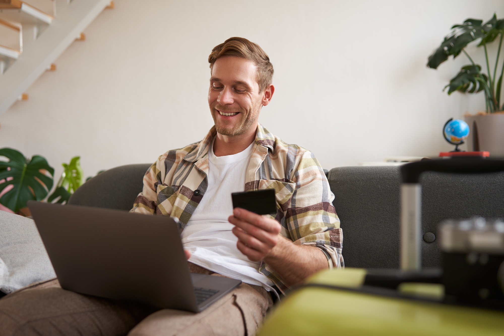 Happy man booking holiday online on laptop, paying for vacation on travel agency website, buying