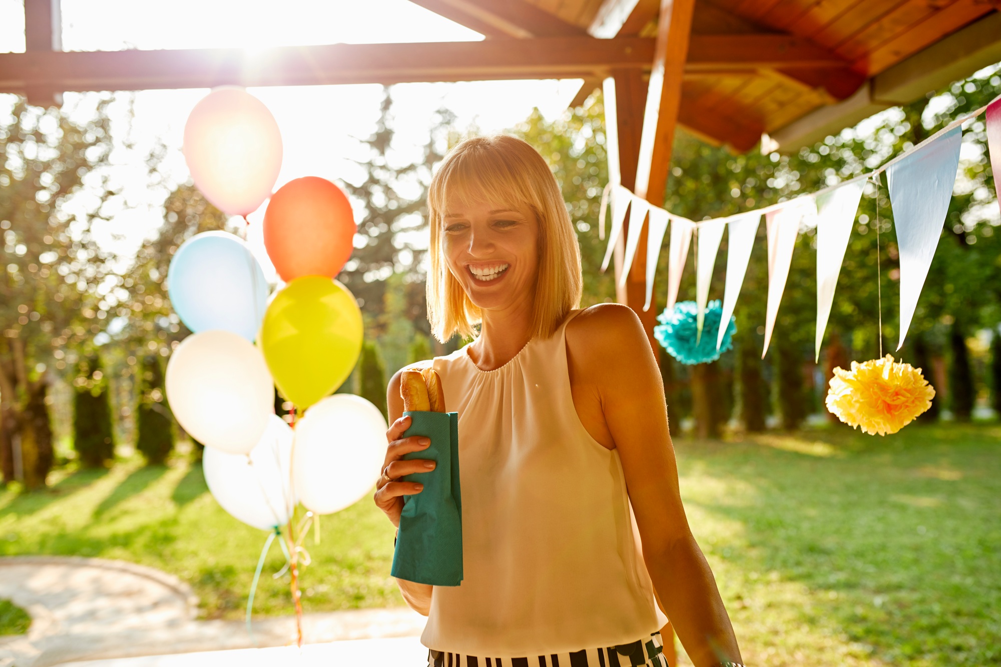 Happy woman eating a hot dog on a garden party