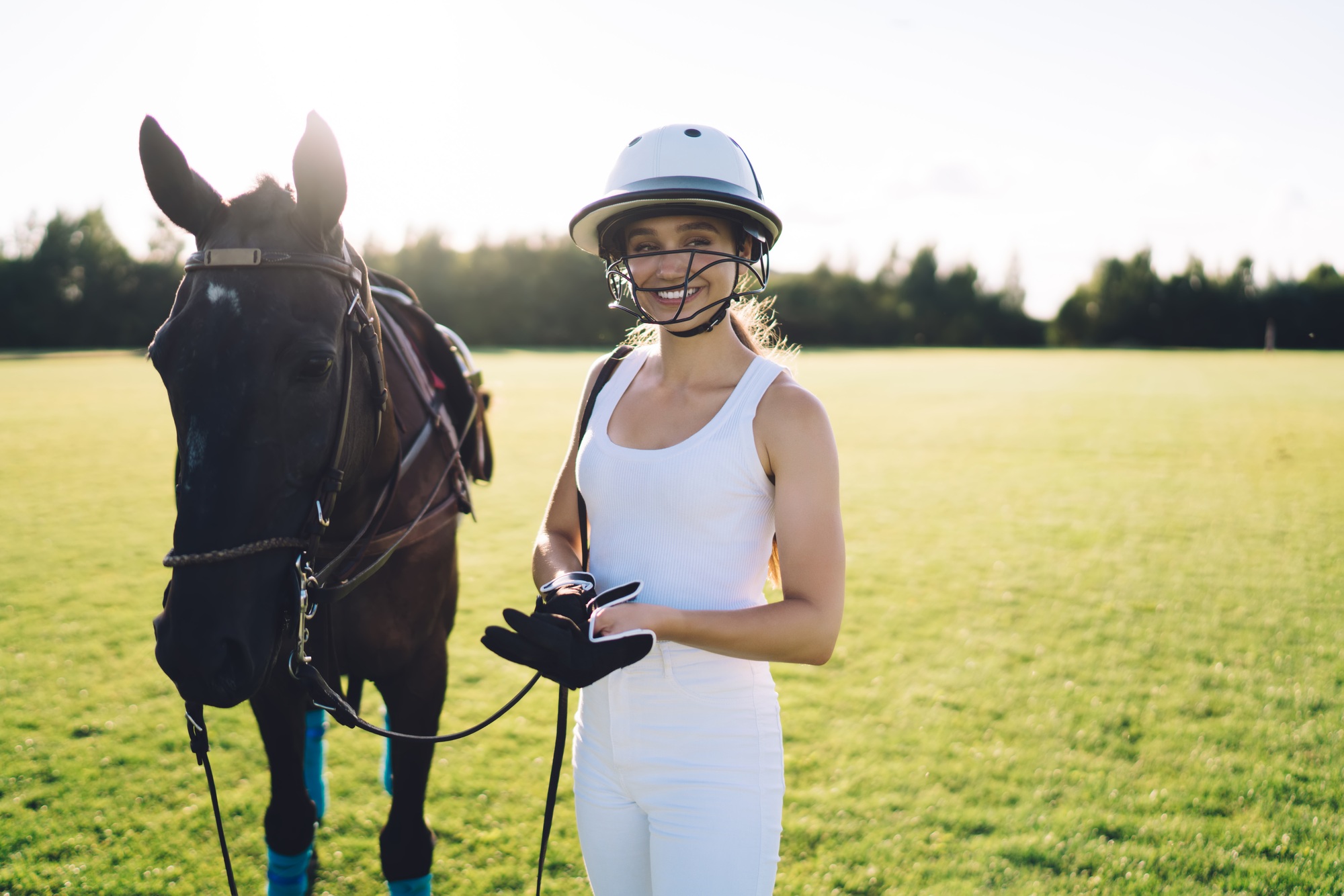 Horsewoman holding horse by reins and smiling at ranch