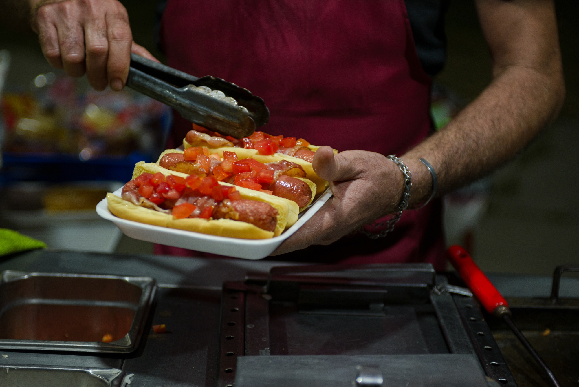Hot Dogs Being Prepared and Served at a Food Stall