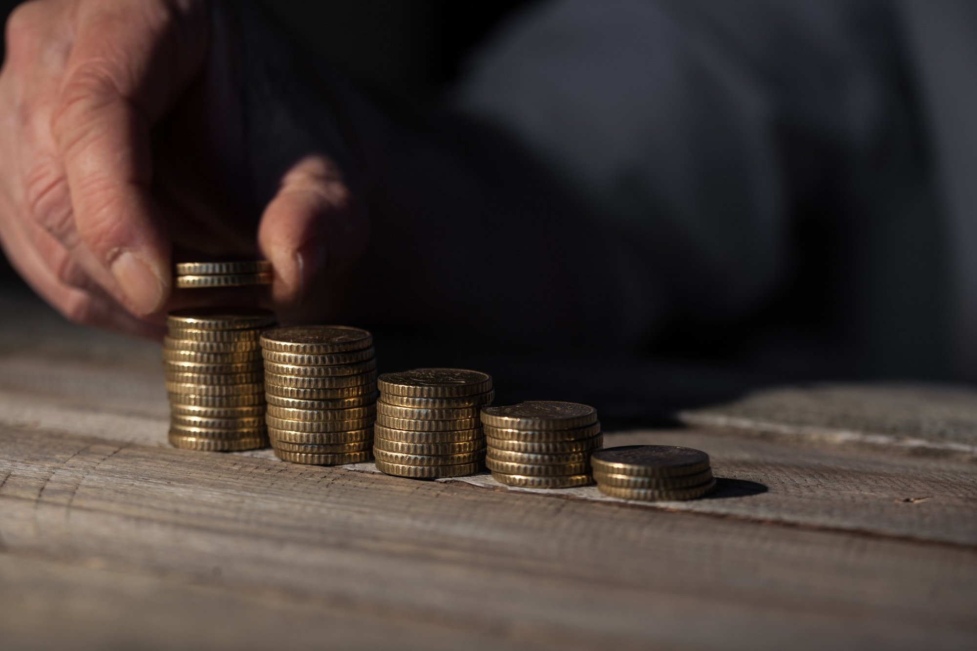 Man in business casual stacking money as concept for success or savings, investment and accounting.
