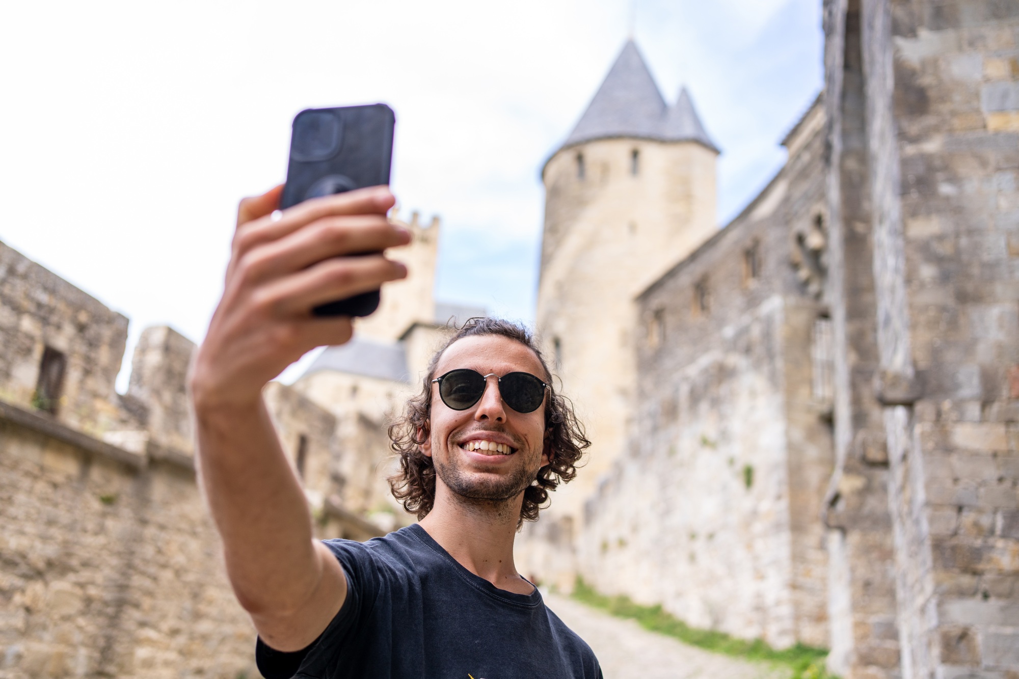 Man with sunglasses taking a selfie with the mobile in a medieval castle