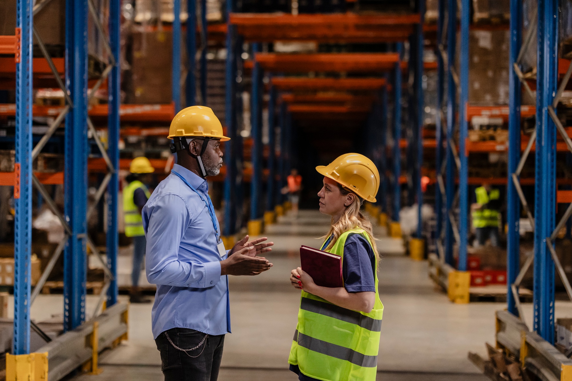 Manager and warehouse worker discussing logistics in a storage facility