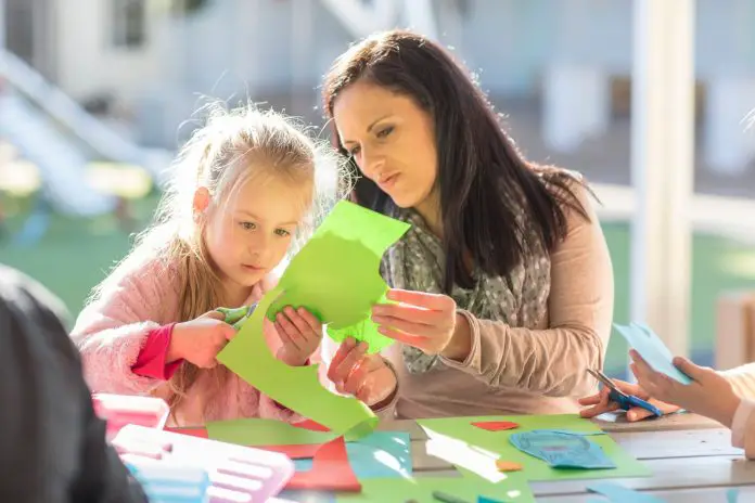 Mid adult woman helping young girl with crafting activity