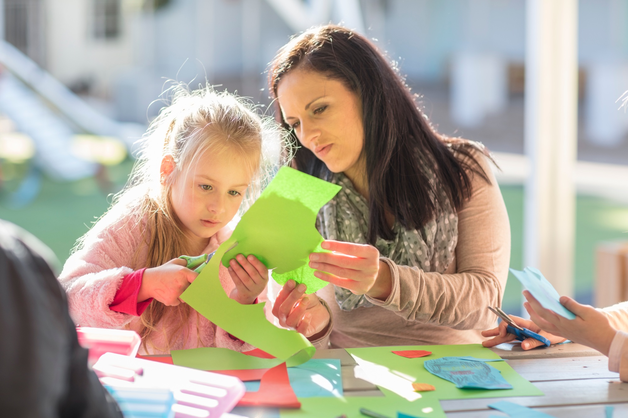 Mid adult woman helping young girl with crafting activity