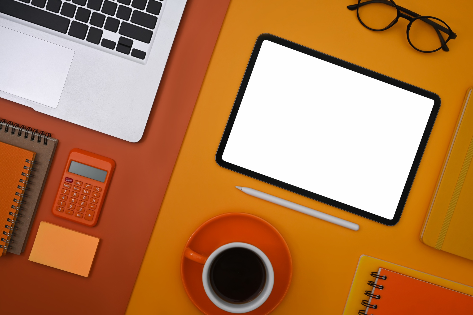 Mockup digital tablet, laptop, coffee cup, and supplies on colorful background. Top view.
