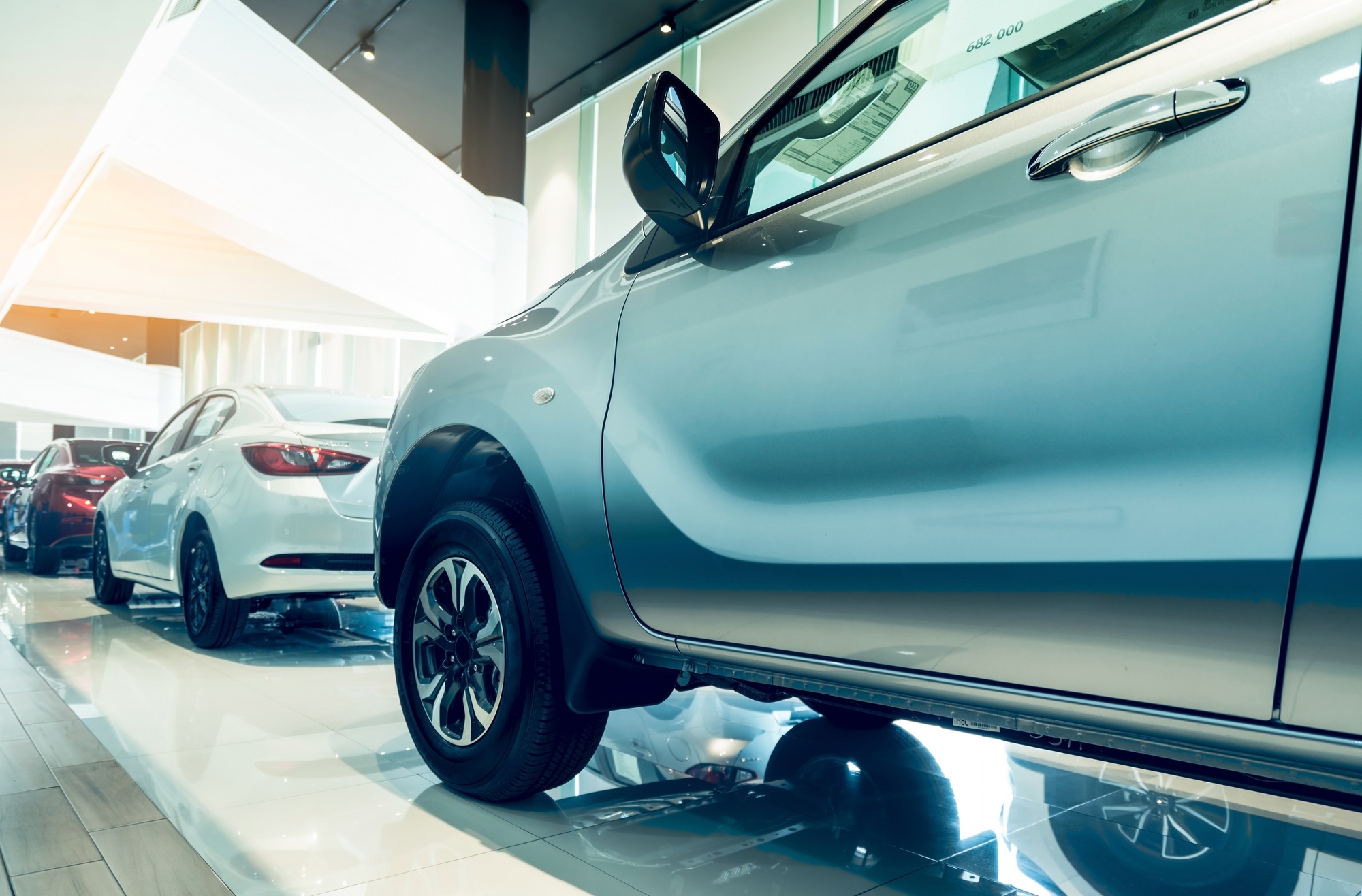 New car parked in modern showroom. Auto leasing and car dealership concept. Red, white, and silver c