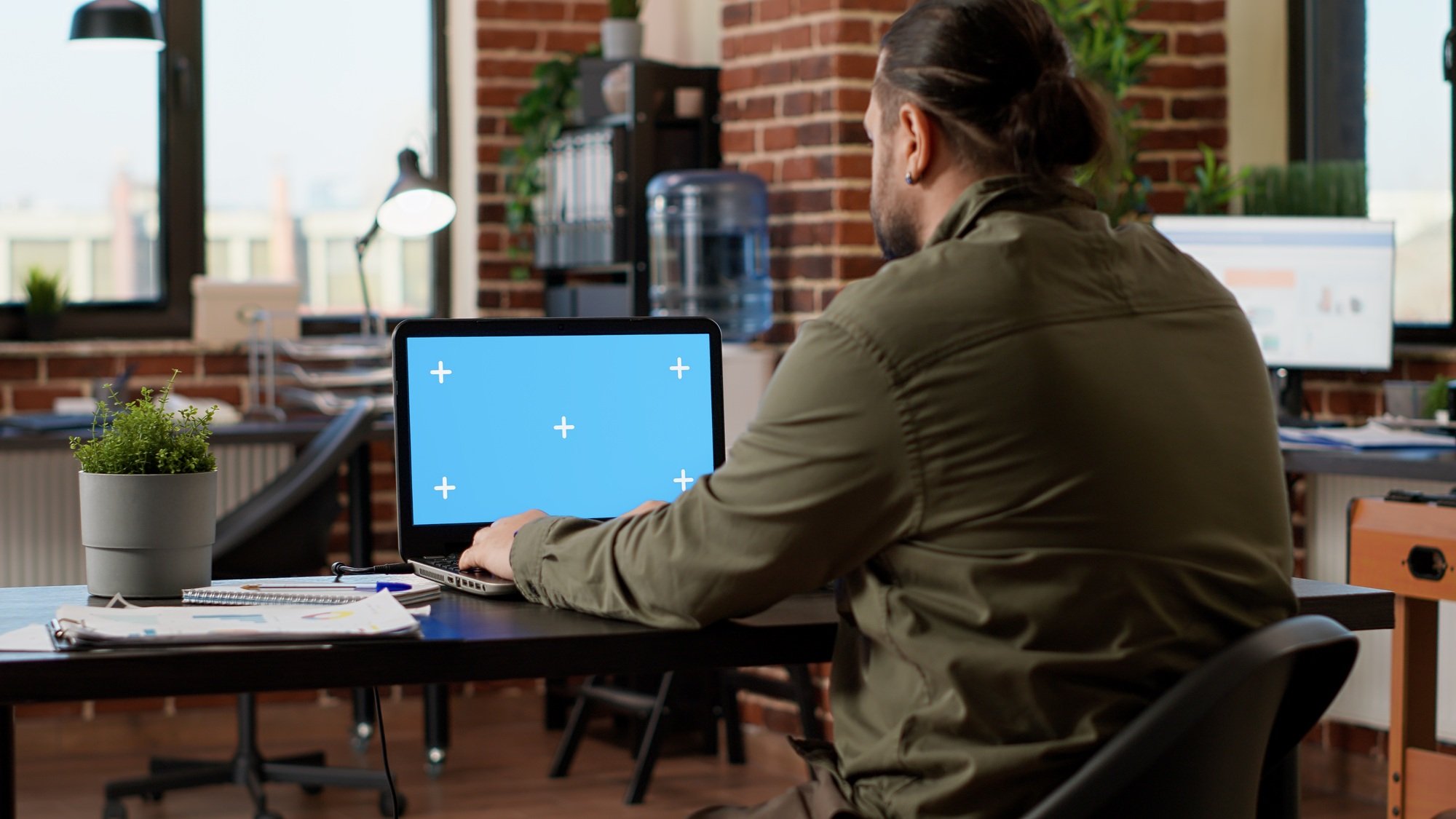 Office worker looking at greenscreen template on laptop