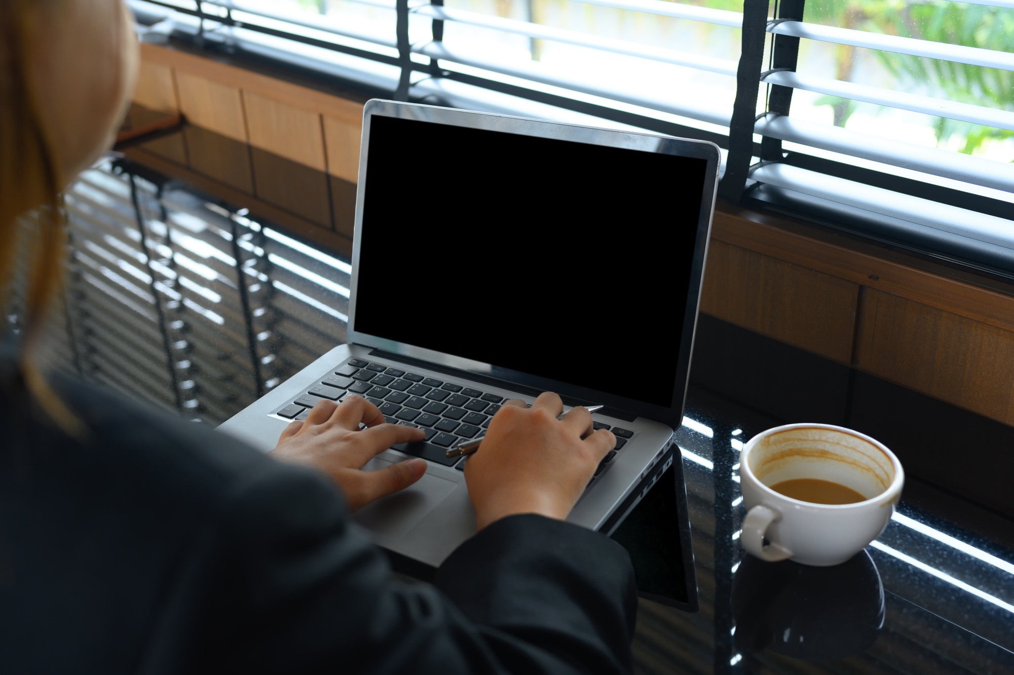 Over shoulder view of businesswoman using laptop on table at modern coffee shop