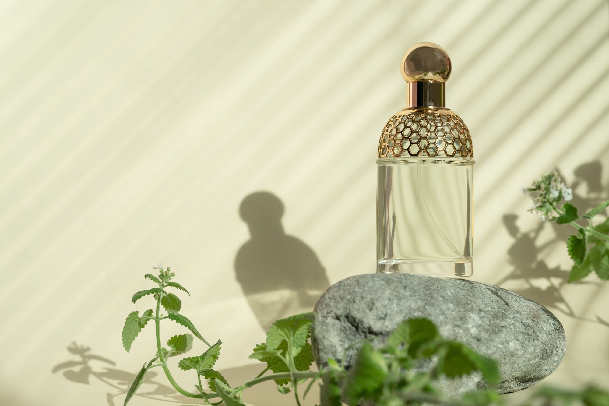 Perfume bottle standing on stone podium. Perfume presentation on the yellow background.