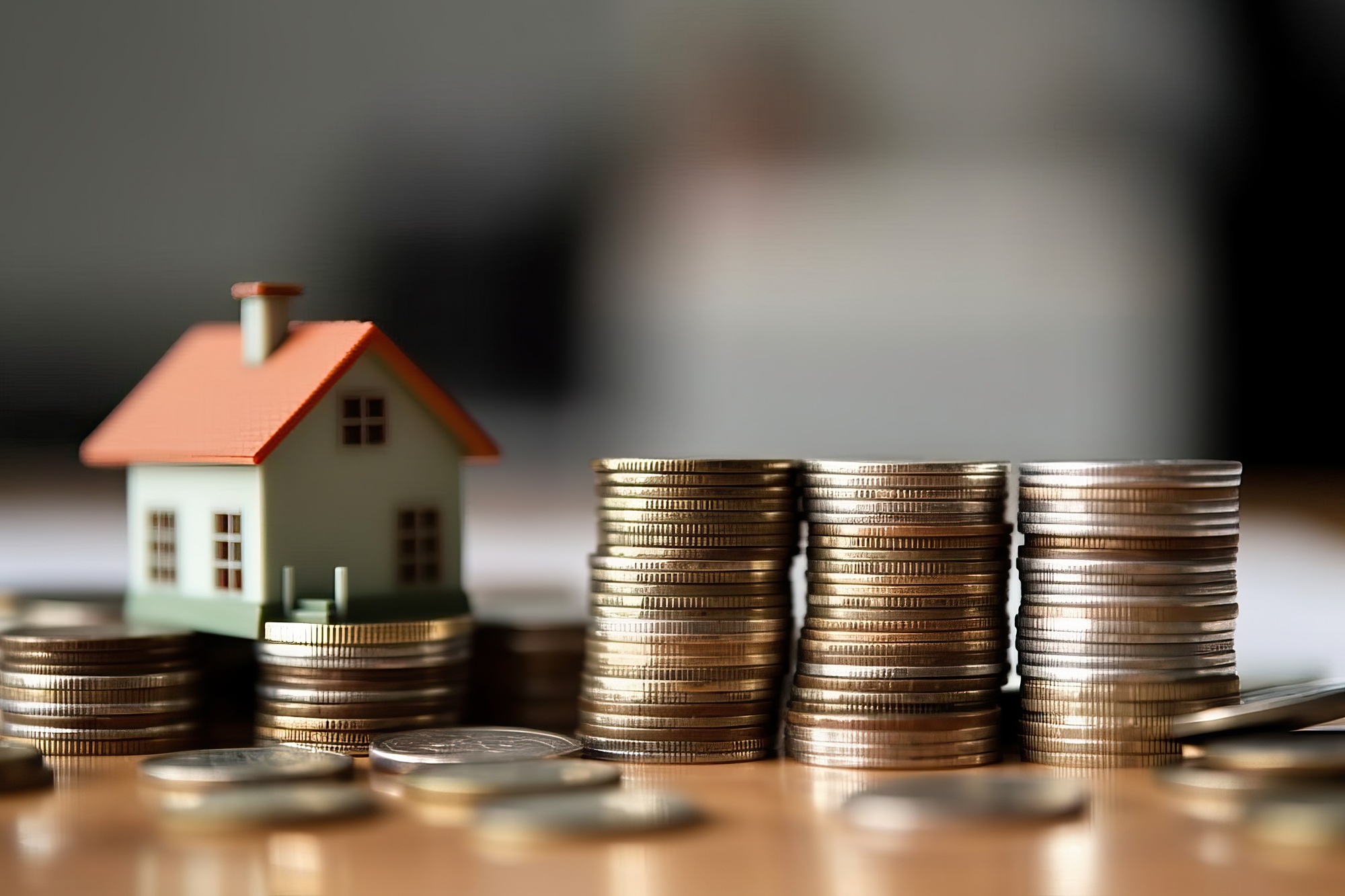 Photo of a house perched on a mound of golden coins, symbolizing real estate wealth and prosperity