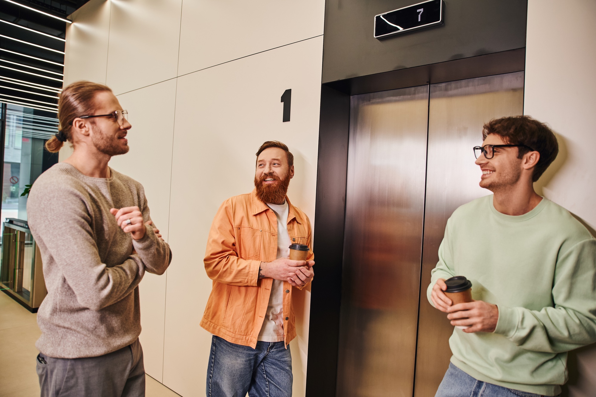 pleased business colleagues in stylish casual clothes holding takeaway drinks in papers cups