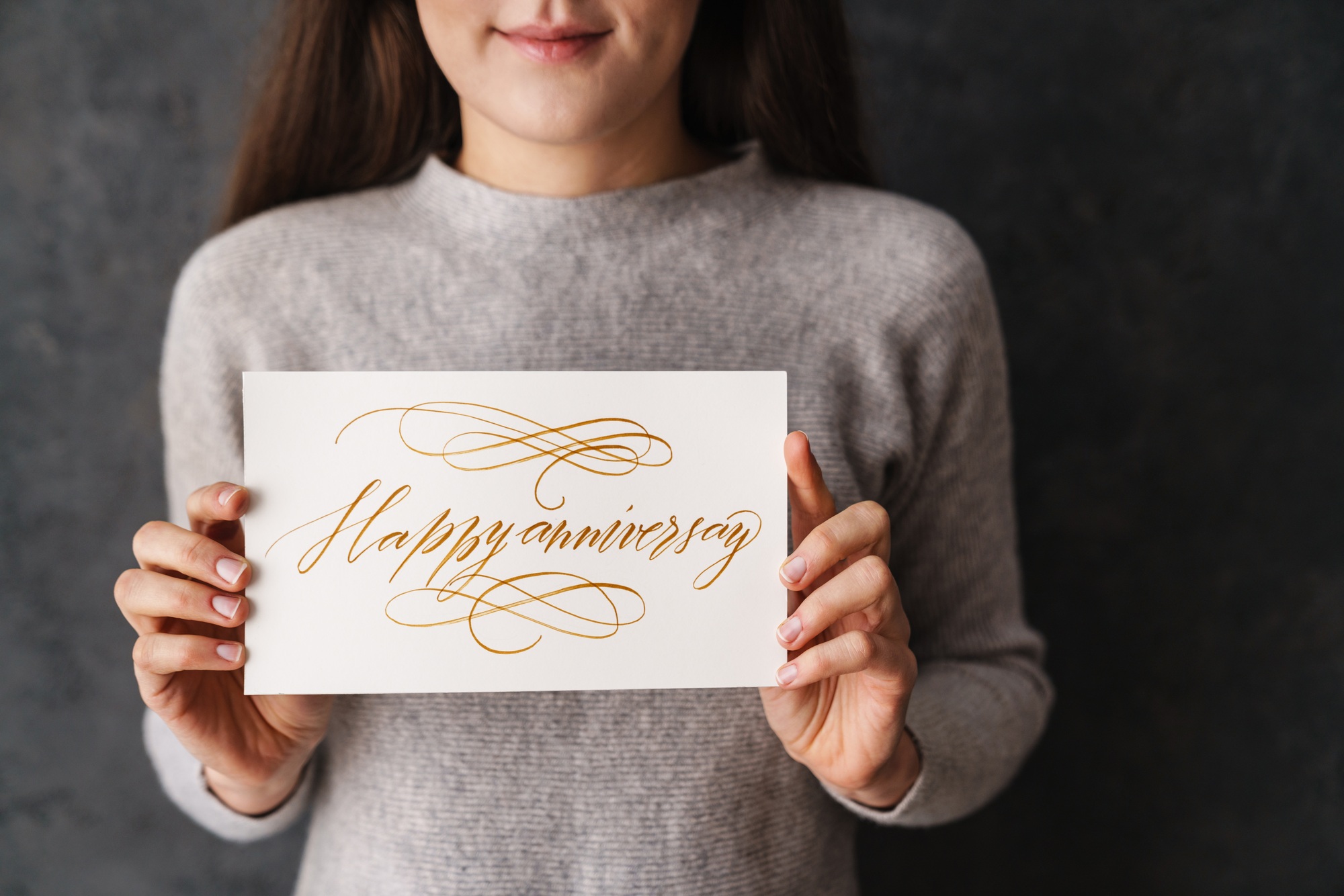 Pleased caucasian girl showing happy anniversary card at camera