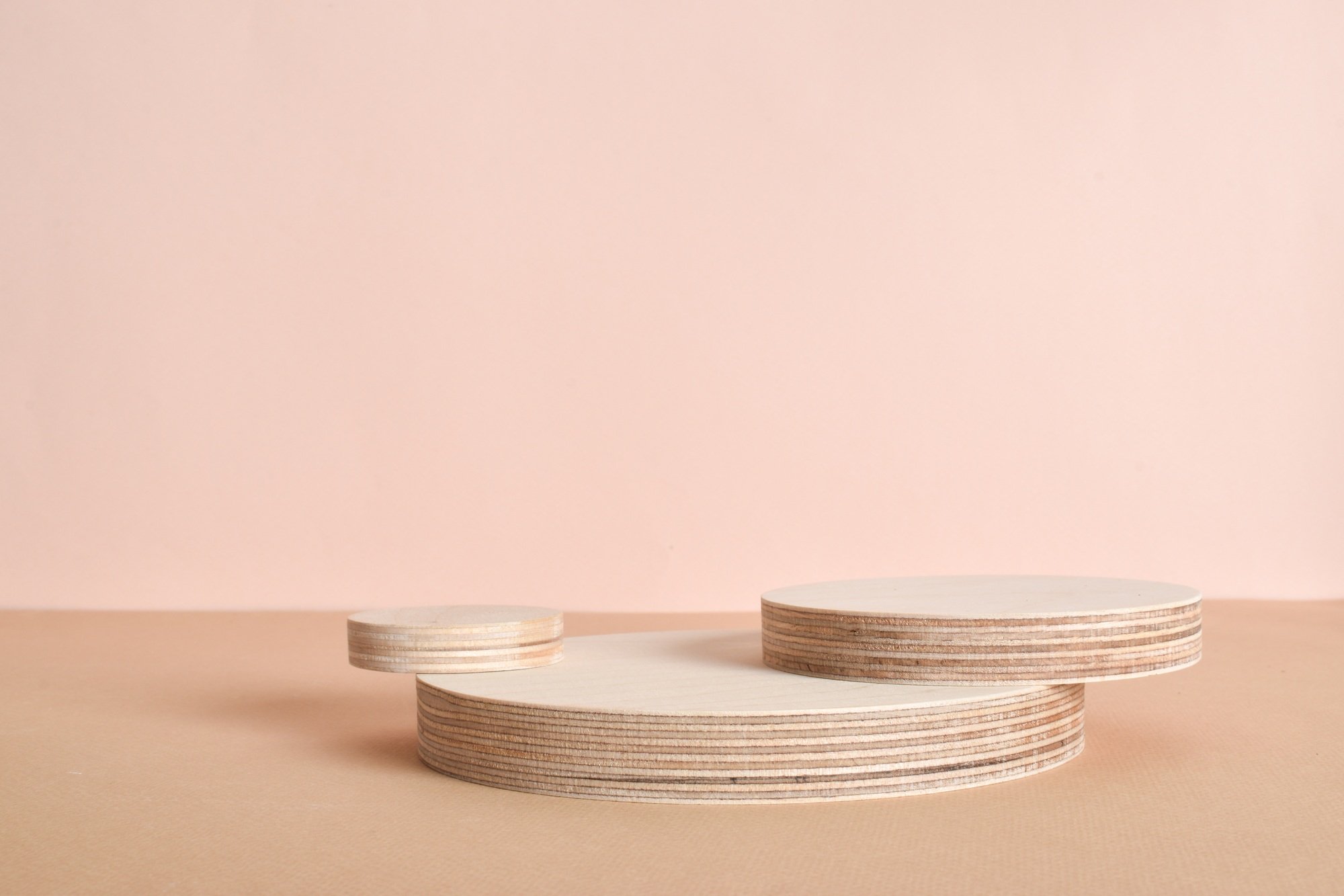 Podium of three wooden cylinders on a beige background. Minimalistic branding scene.