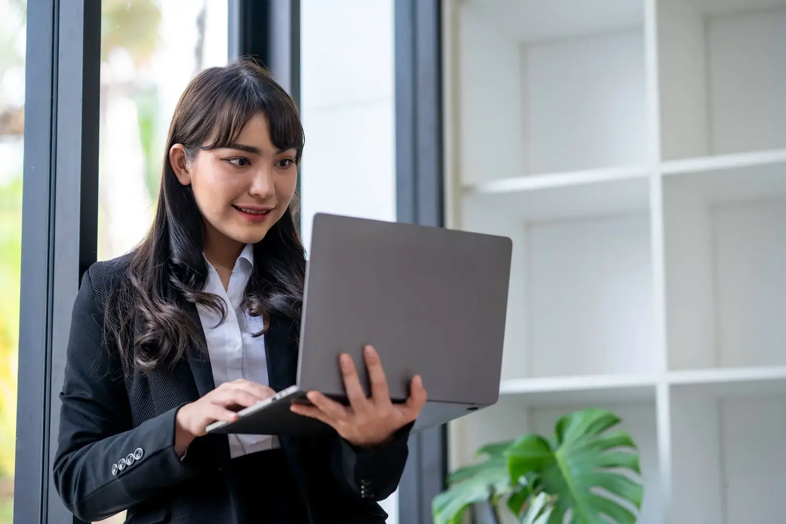 Portrait of businesswoman standing Using Laptop in office working on laptop typing business e-mail,