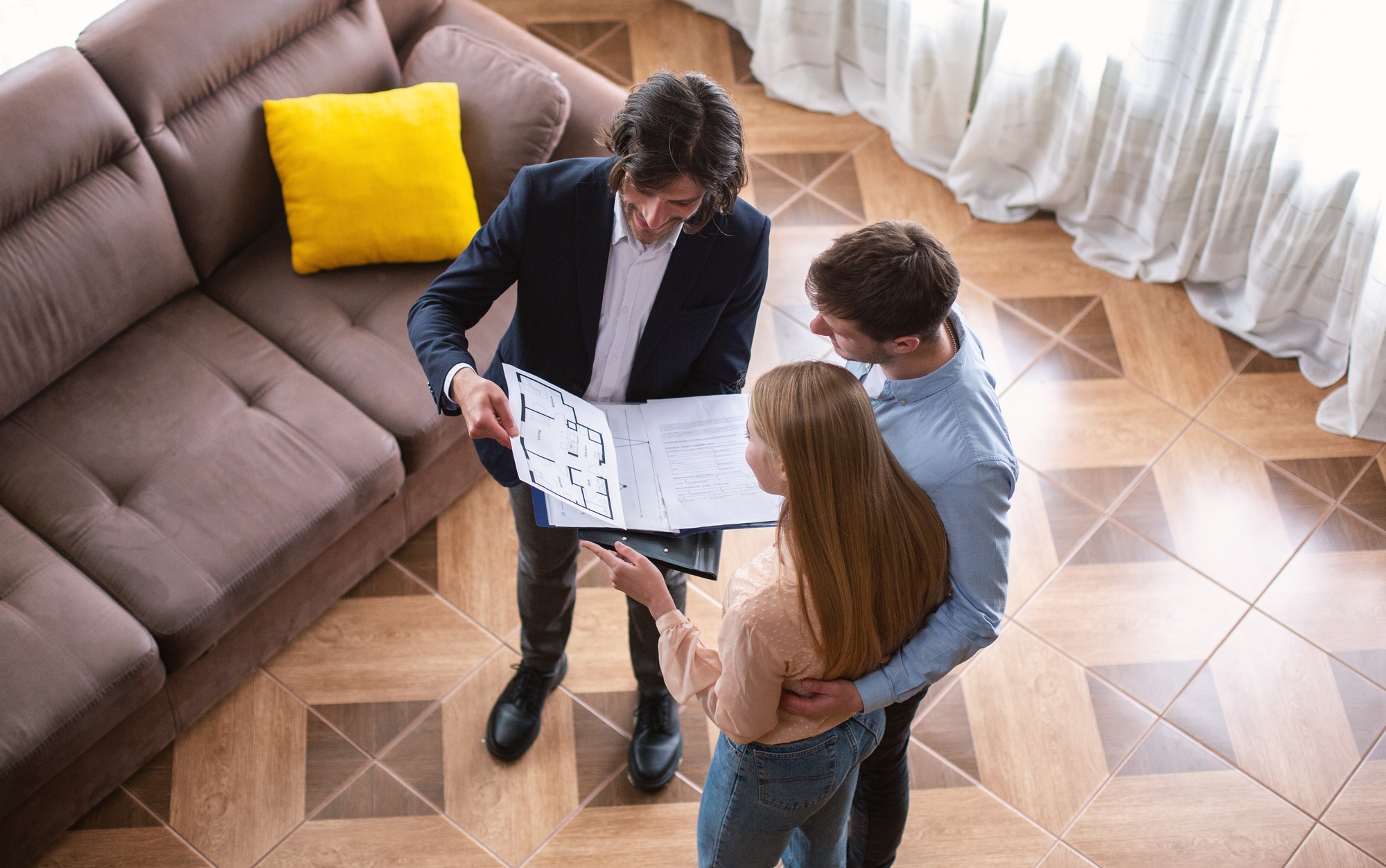Real estate business. Above view of realtor showing house plan to customers indoor