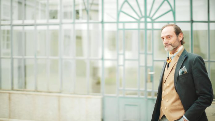 Senior businessman with confident stance near glass structure.