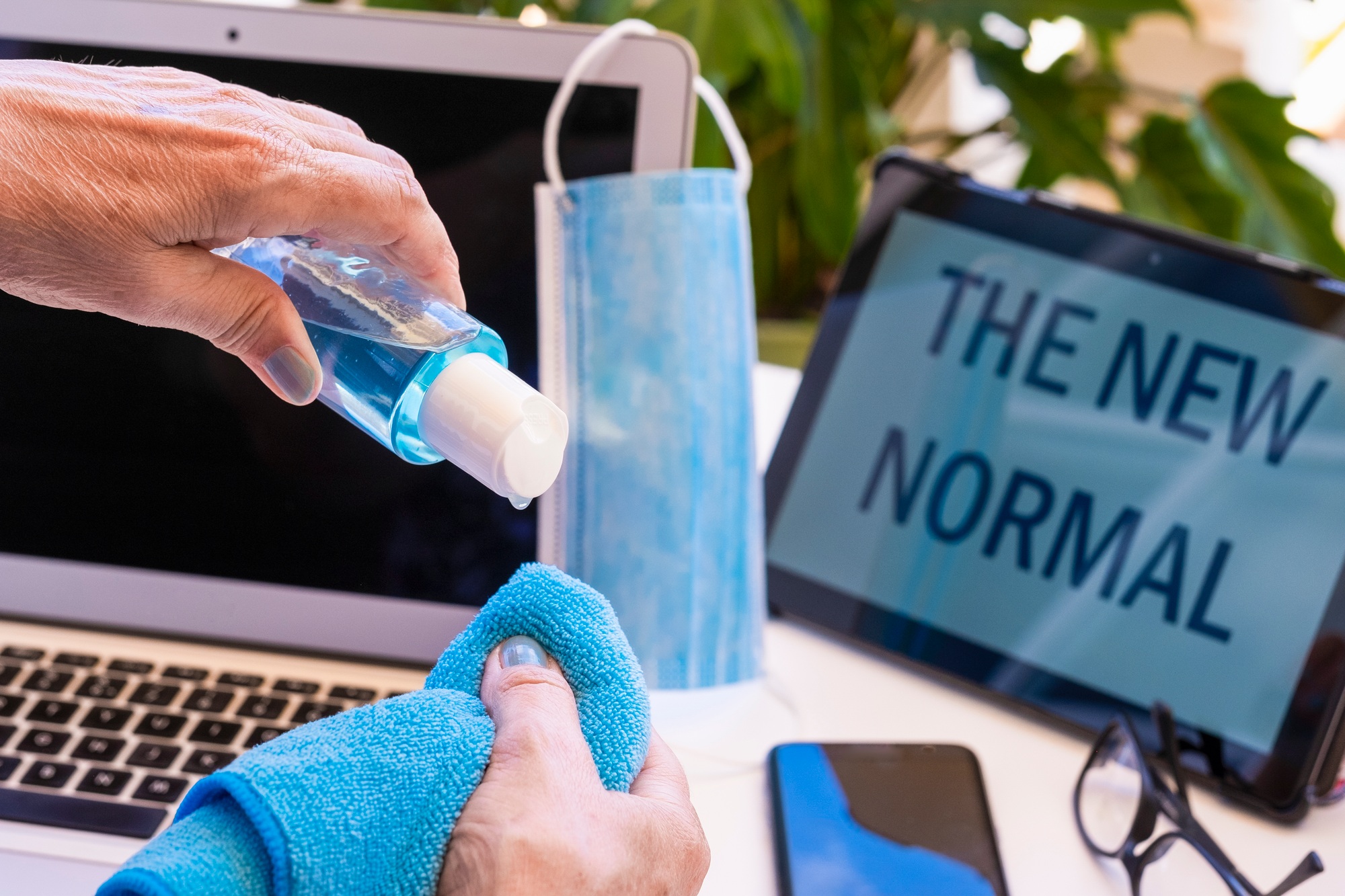 Senior woman cleaning and disinfecting the laptop computer at home - the new normal