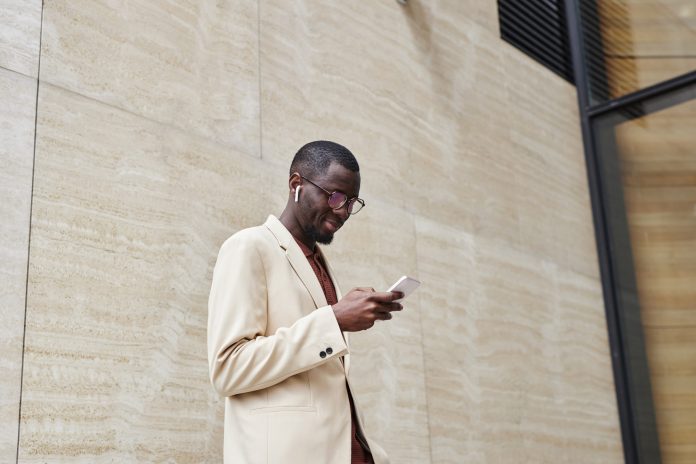 Side view of young confident chief executive officer using smartphone