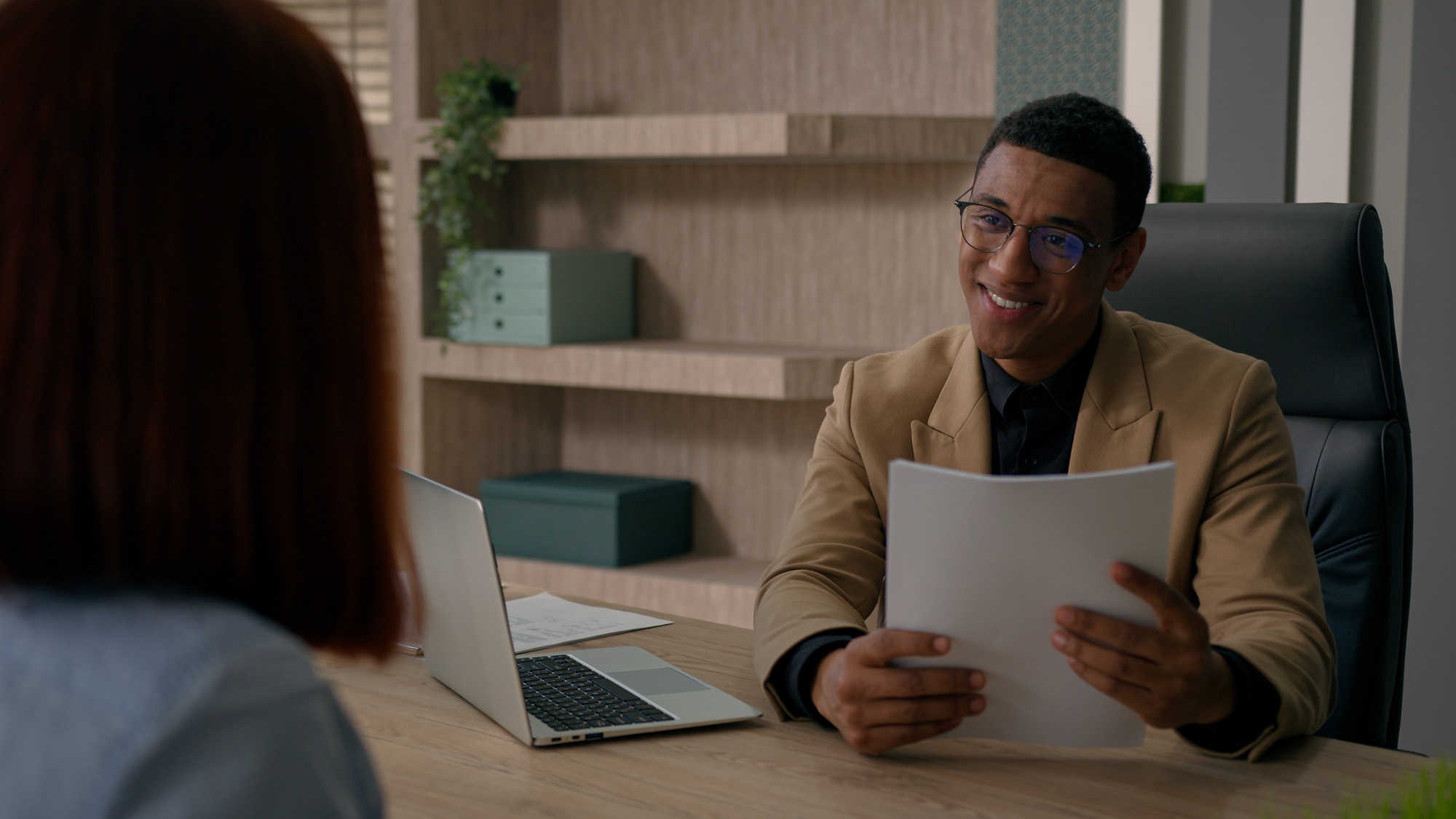 Smiling African American businessman man employer talk to woman hiring candidate job interview take
