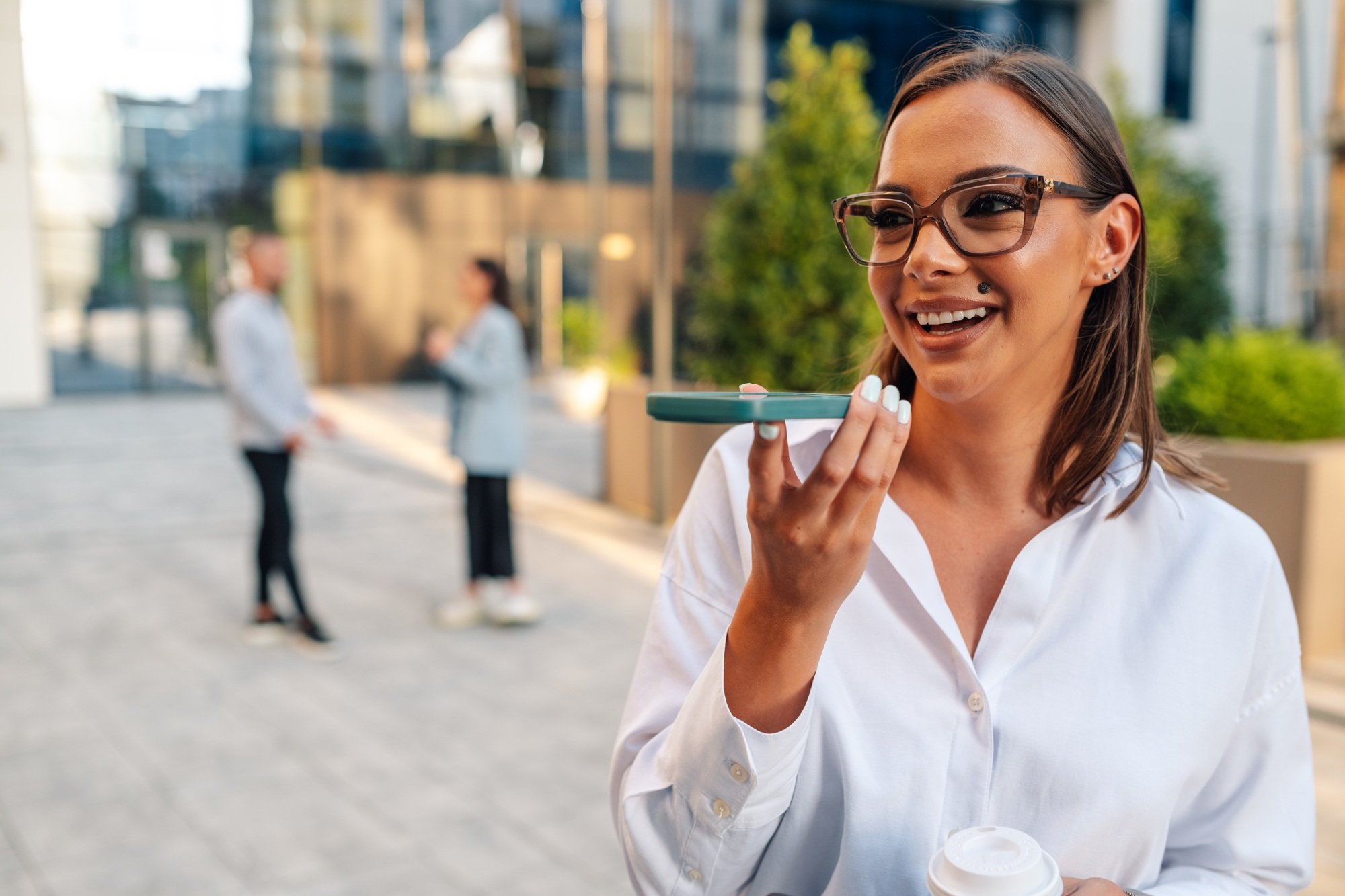 Smiling businesswoman using personal assistant on smartphone outdoors