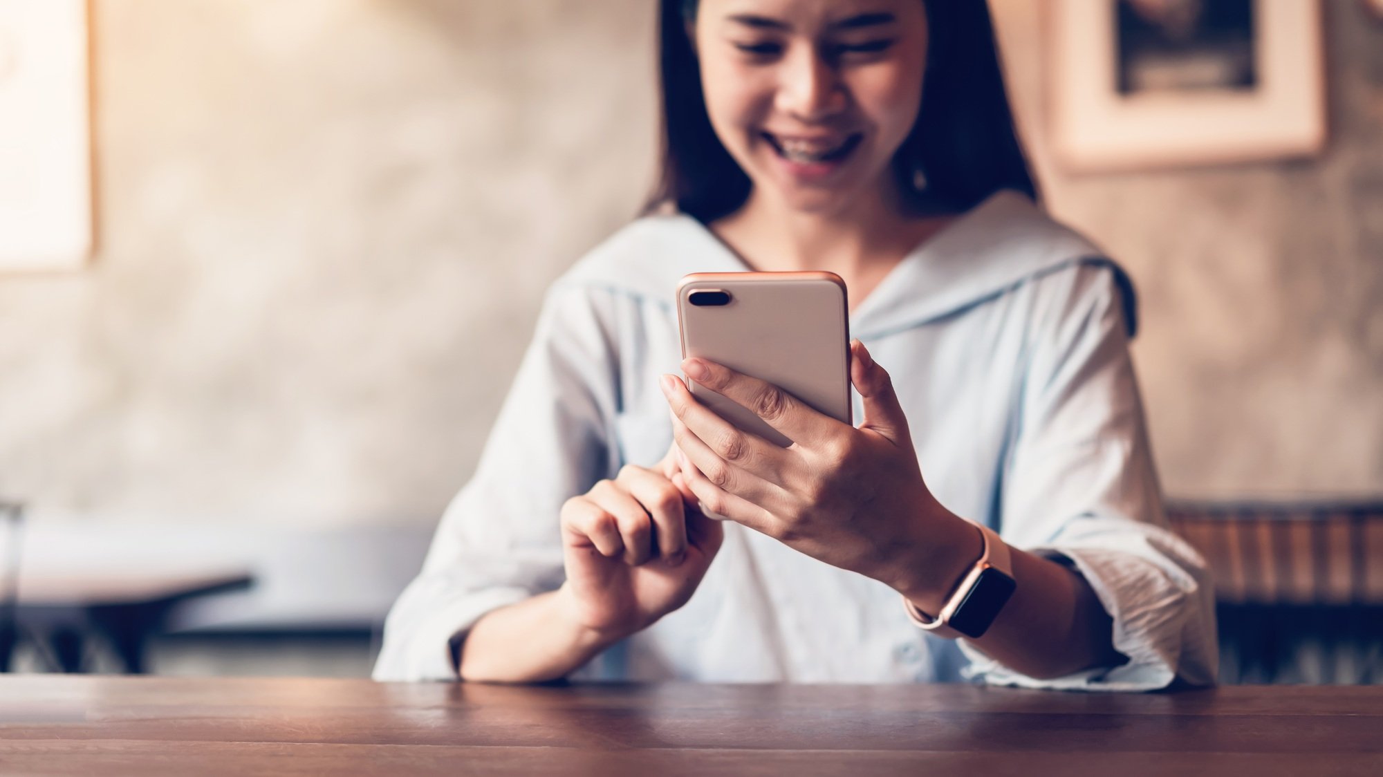 Smiling of asian woman using smartphone texting on the cafe. copy space for ads.