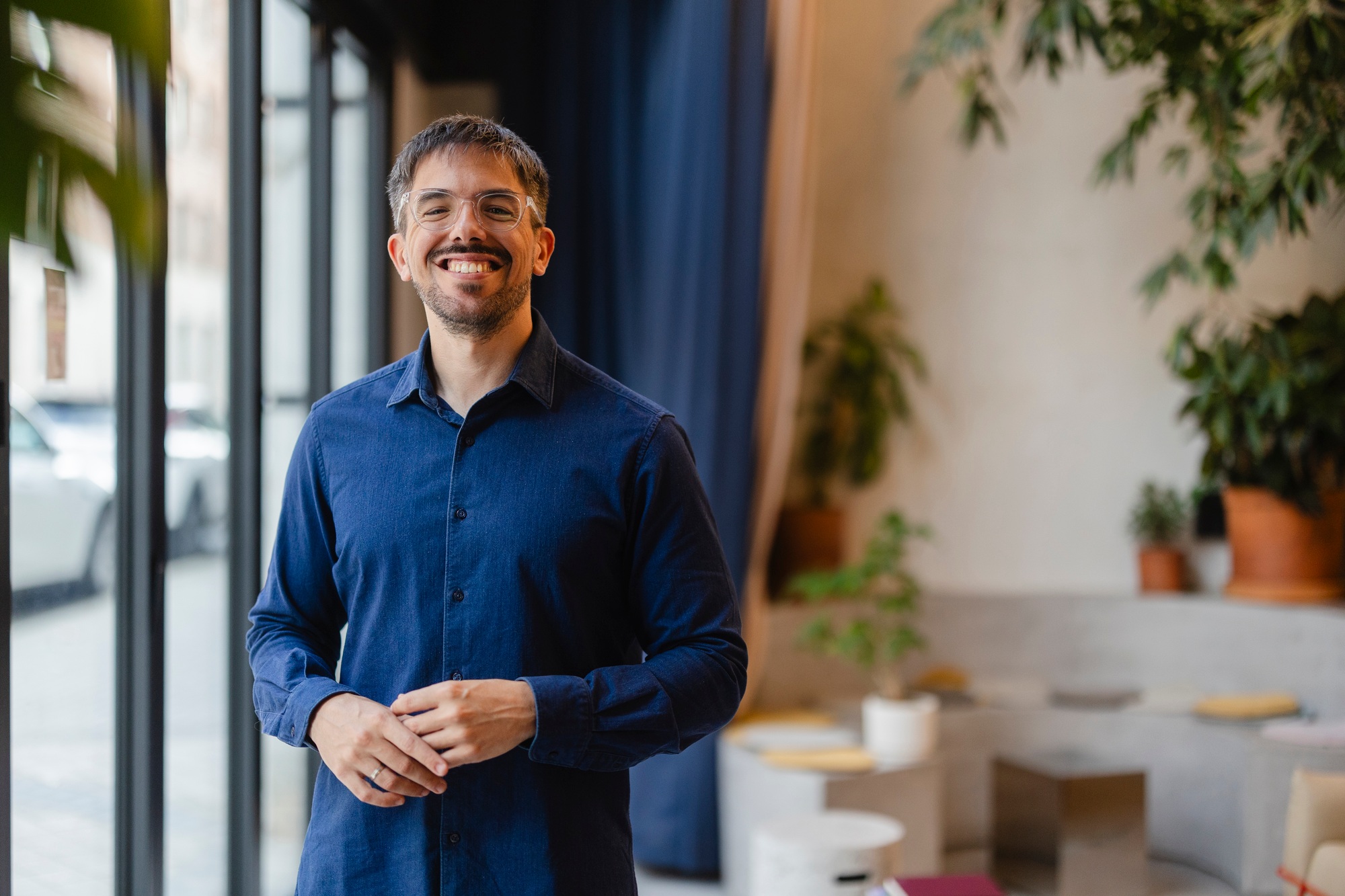 Startup founder smiling in modern office with plants, embracing green workspace design