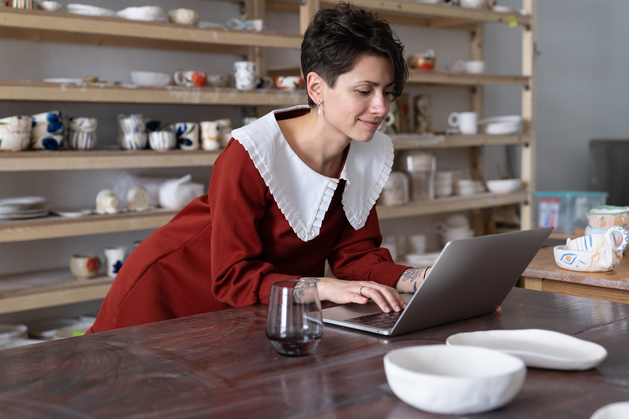 Successful female artisan using craft platform to sell pottery items, crafswoman using laptop