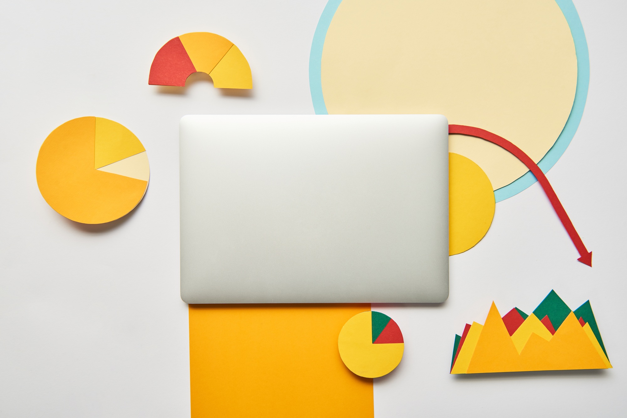 top view of closed laptop and paper charts and graphs, pointer, sheet of paper on white background